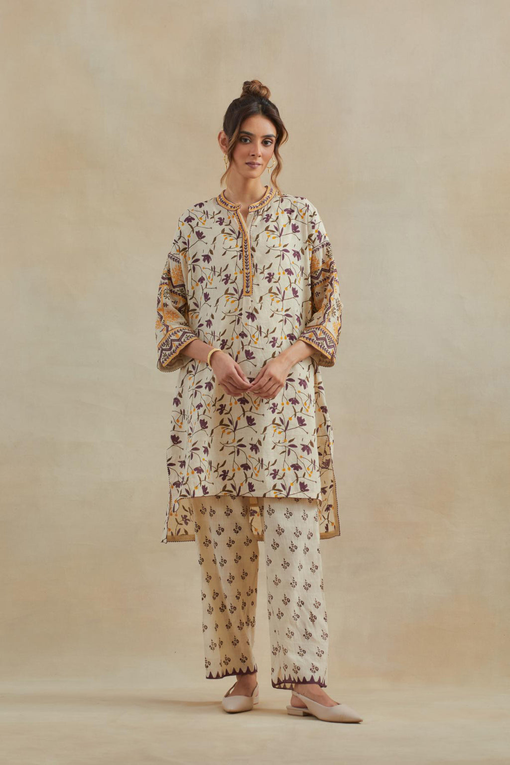 Beige cotton easy fit short kurta with all-over yellow & purple hand block print, highlighted with silk thread embroidery, paired with beige cotton straight pants with all-over small booti hand block print.