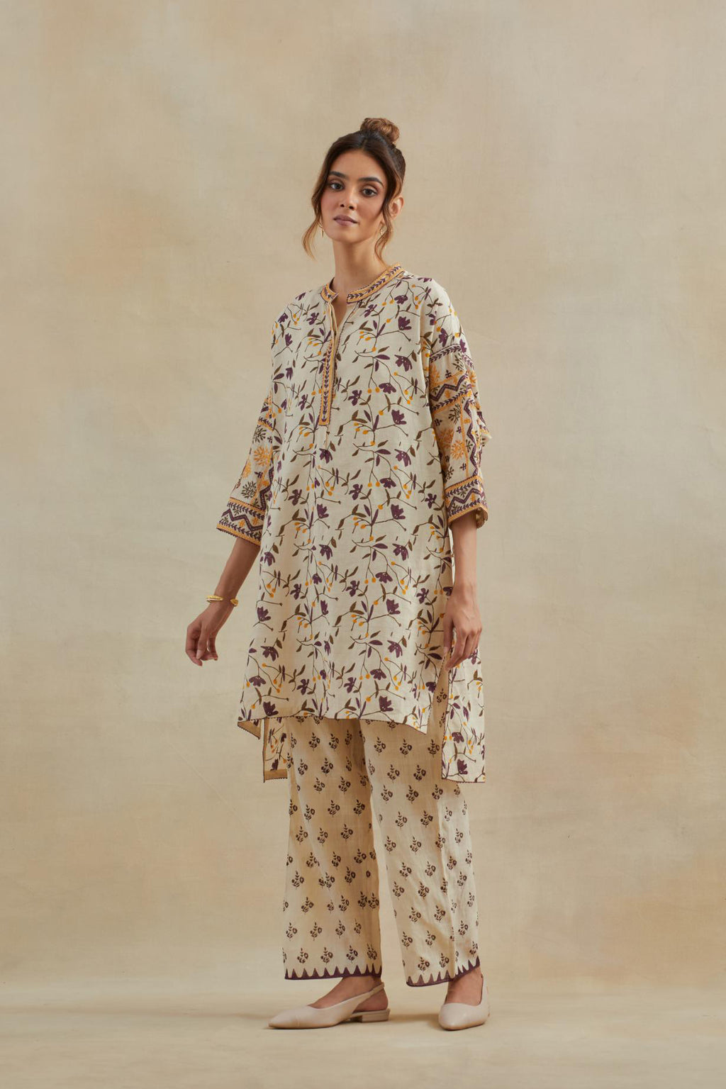 Beige cotton easy fit short kurta with all-over yellow & purple hand block print, highlighted with silk thread embroidery, paired with beige cotton straight pants with all-over small booti hand block print.
