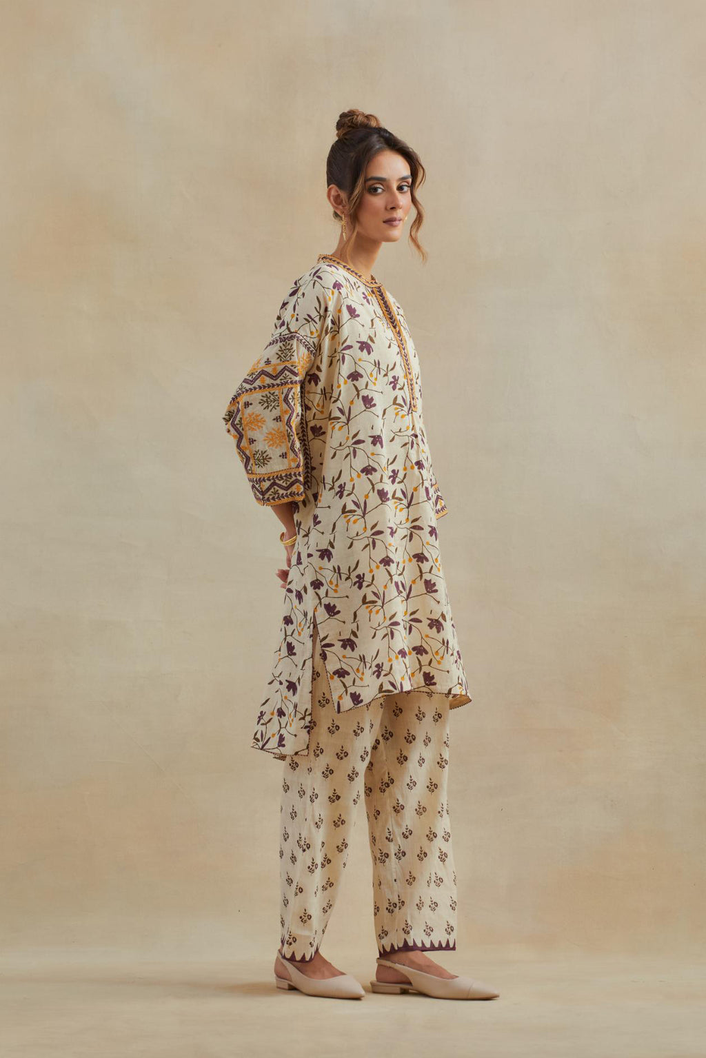 Beige cotton easy fit short kurta with all-over yellow & purple hand block print, highlighted with silk thread embroidery, paired with beige cotton straight pants with all-over small booti hand block print.