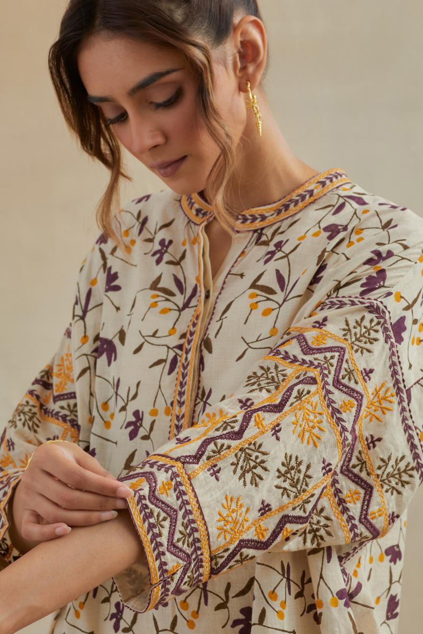 Beige cotton easy fit short kurta with all-over yellow & purple hand block print, highlighted with silk thread embroidery, paired with beige cotton straight pants with all-over small booti hand block print.