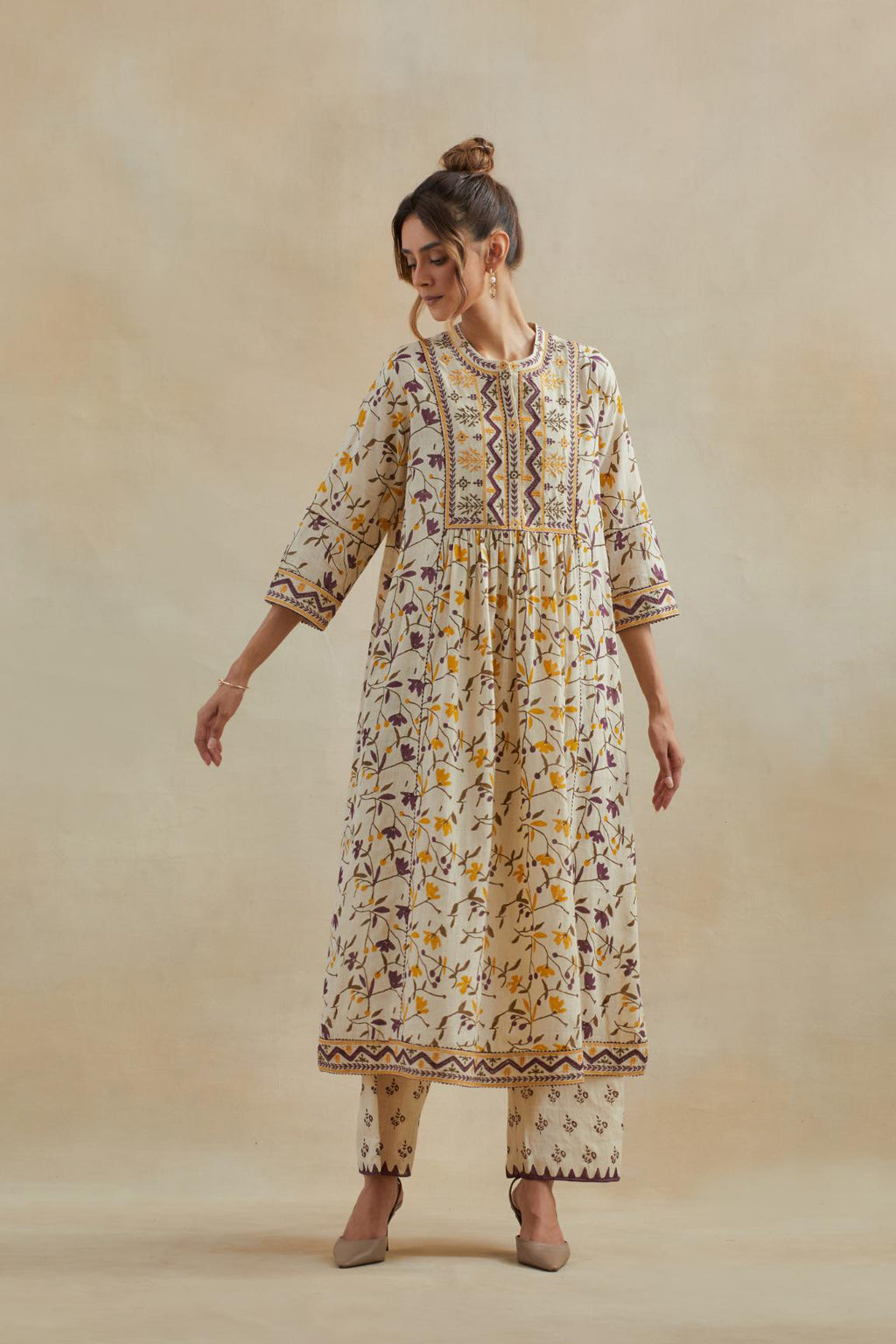 A beige cotton kurta dress set featuring an all-over yellow and purple flower hand block print.