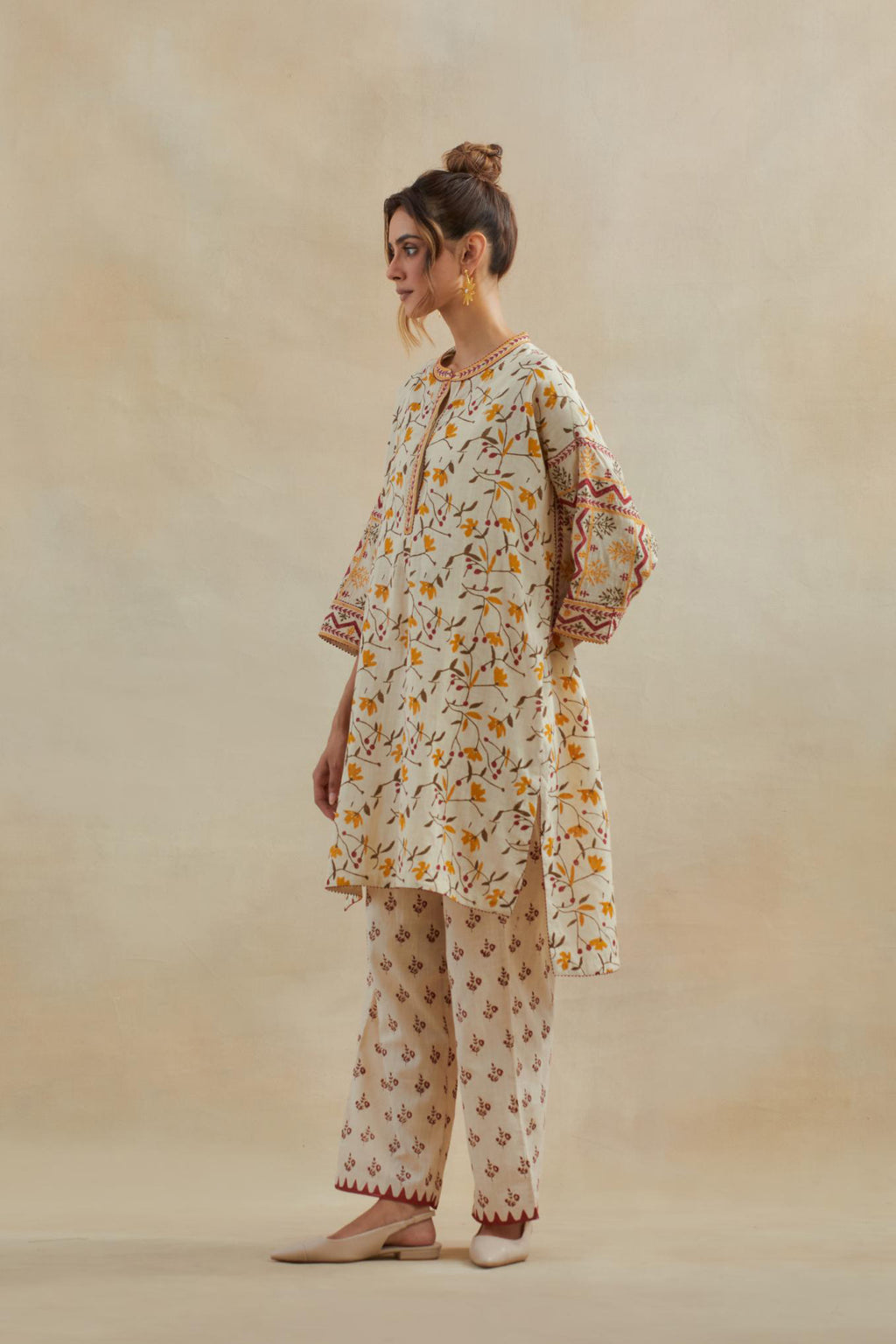 Beige cotton easy fit short kurta with all-over yellow & rust hand block print, highlighted with silk thread embroidery, paired with beige cotton straight pants with all-over small booti hand block print.