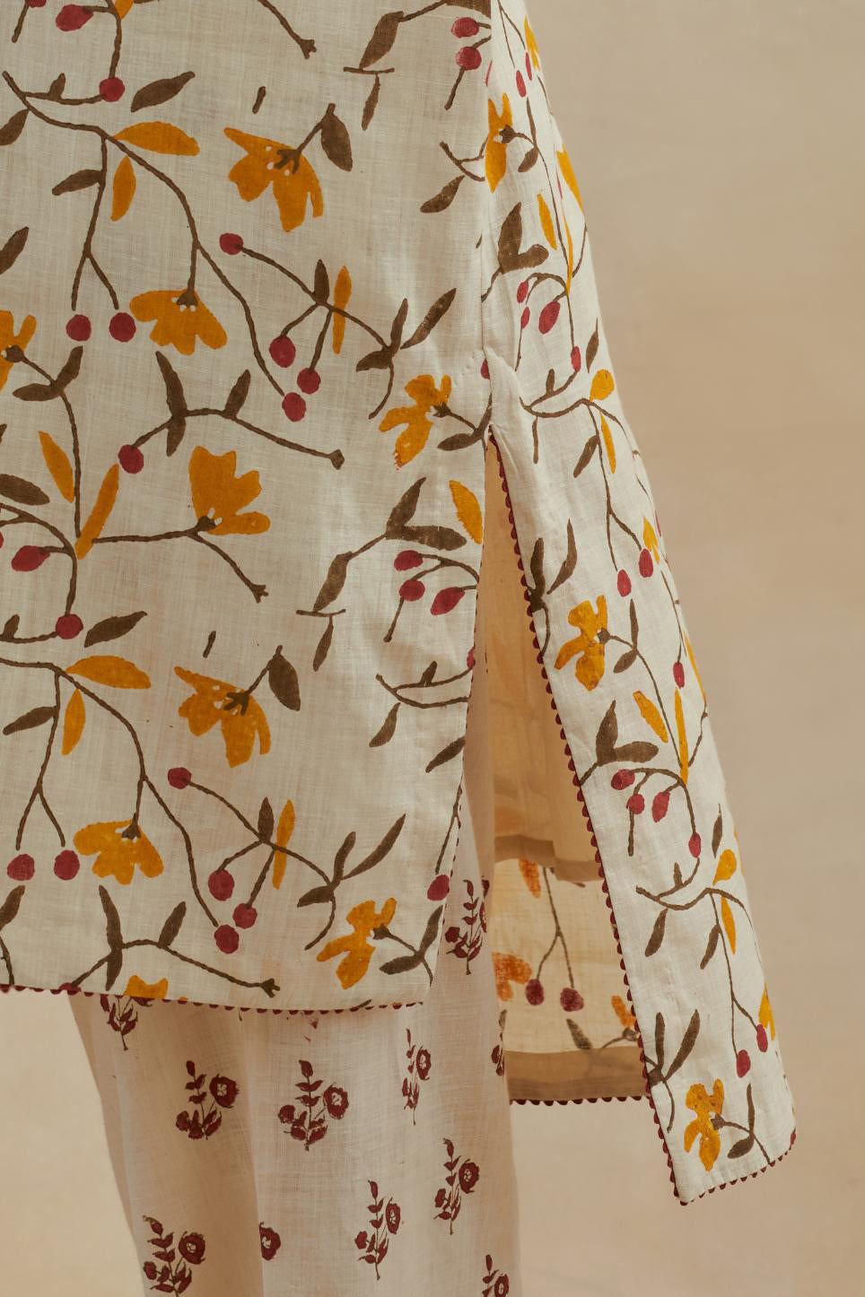 Beige cotton easy fit short kurta with all-over yellow & rust hand block print, highlighted with silk thread embroidery, paired with beige cotton straight pants with all-over small booti hand block print.