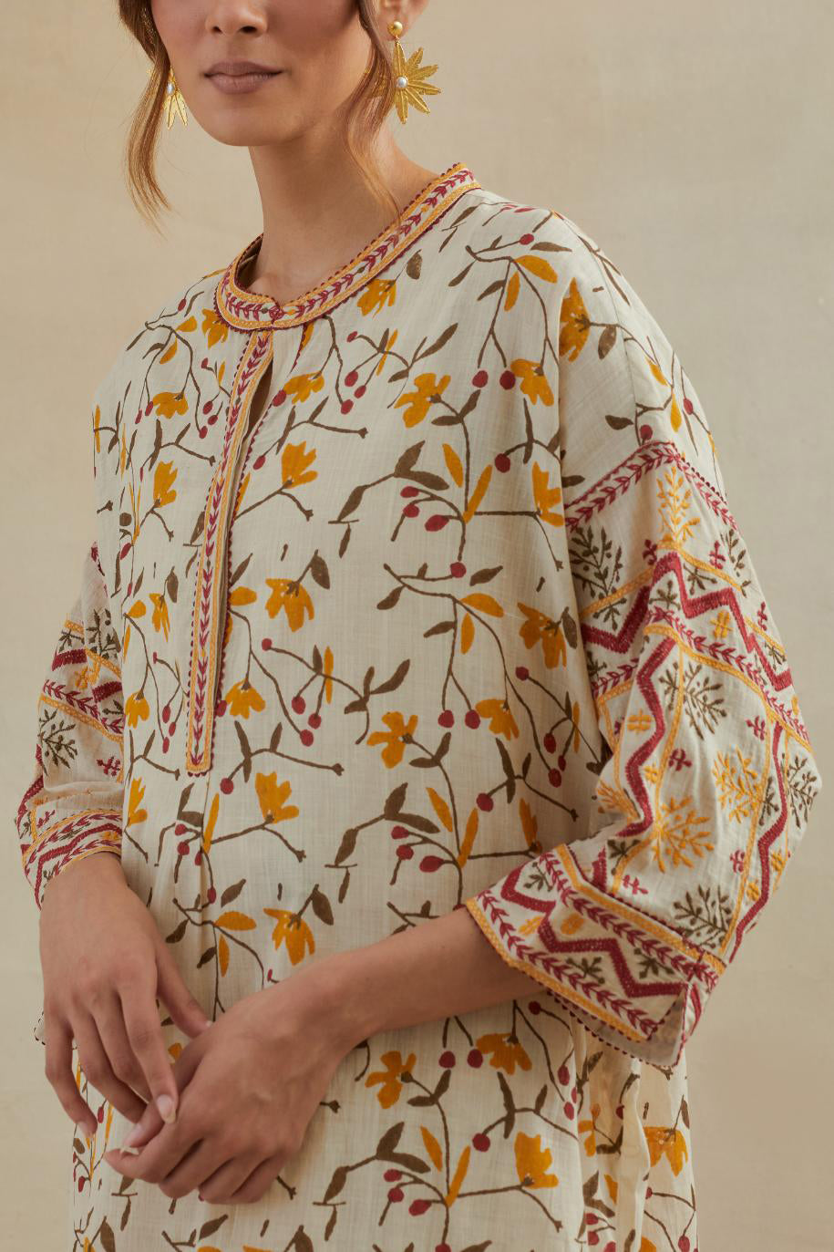 Beige cotton easy fit short kurta with all-over yellow & rust hand block print, highlighted with silk thread embroidery, paired with beige cotton straight pants with all-over small booti hand block print.