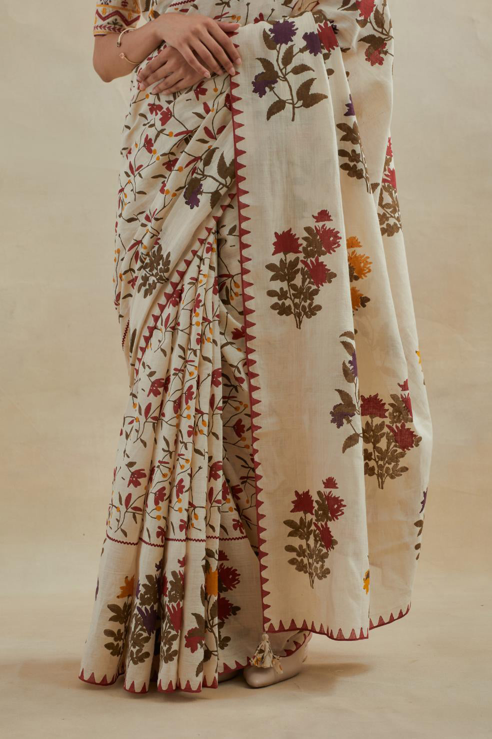 Beige cotton saree with all-over multi colored floral jaal hand block print and boota at saree hem and pallu, paired with beige cotton blouse with all-over multi colored thread embroidery.