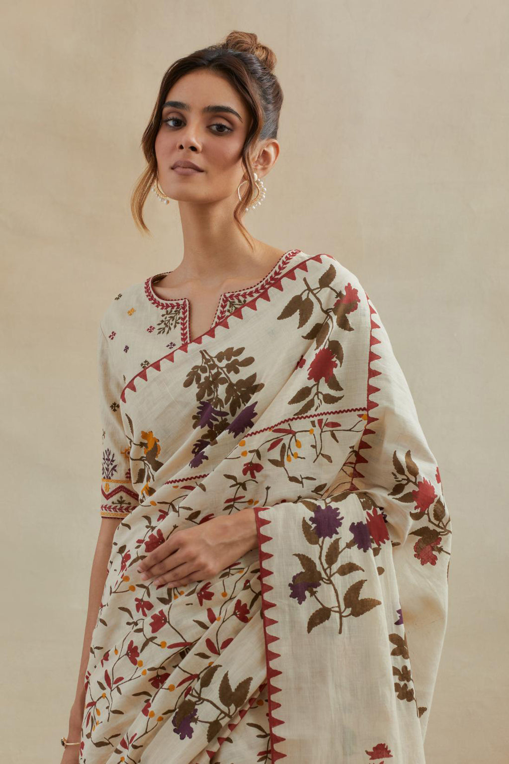 Beige cotton saree with all-over multi colored floral jaal hand block print and boota at saree hem and pallu, paired with beige cotton blouse with all-over multi colored thread embroidery.