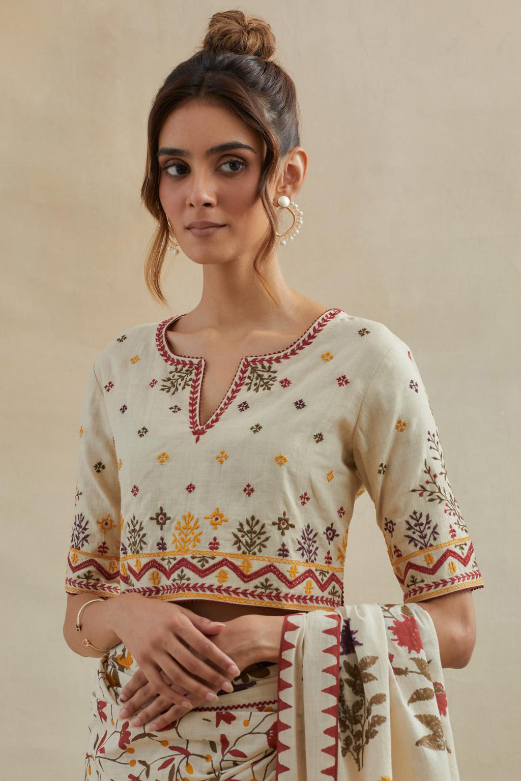 Beige cotton blouse with all-over multi colored thread embroidery.