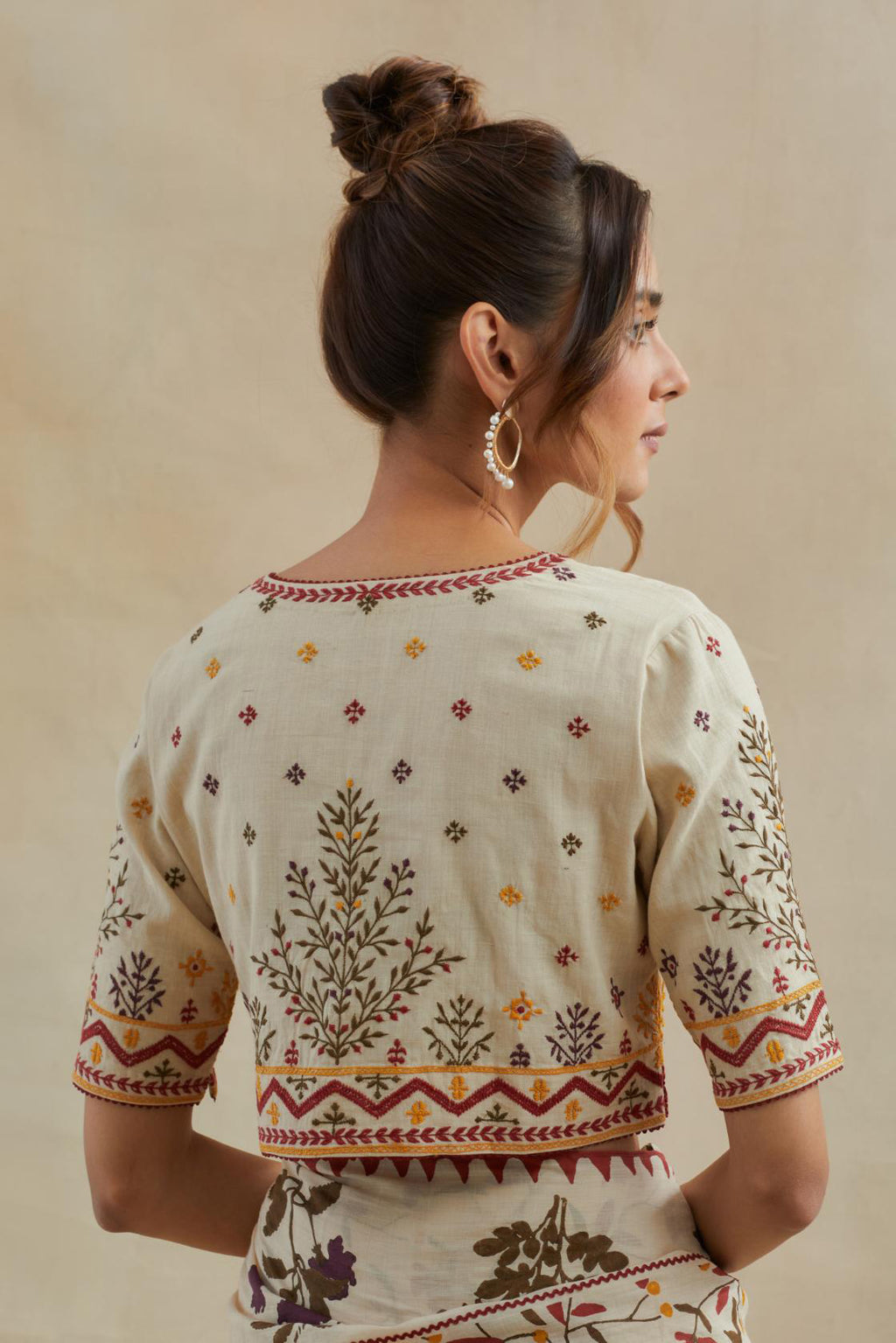 Beige cotton blouse with all-over multi colored thread embroidery.