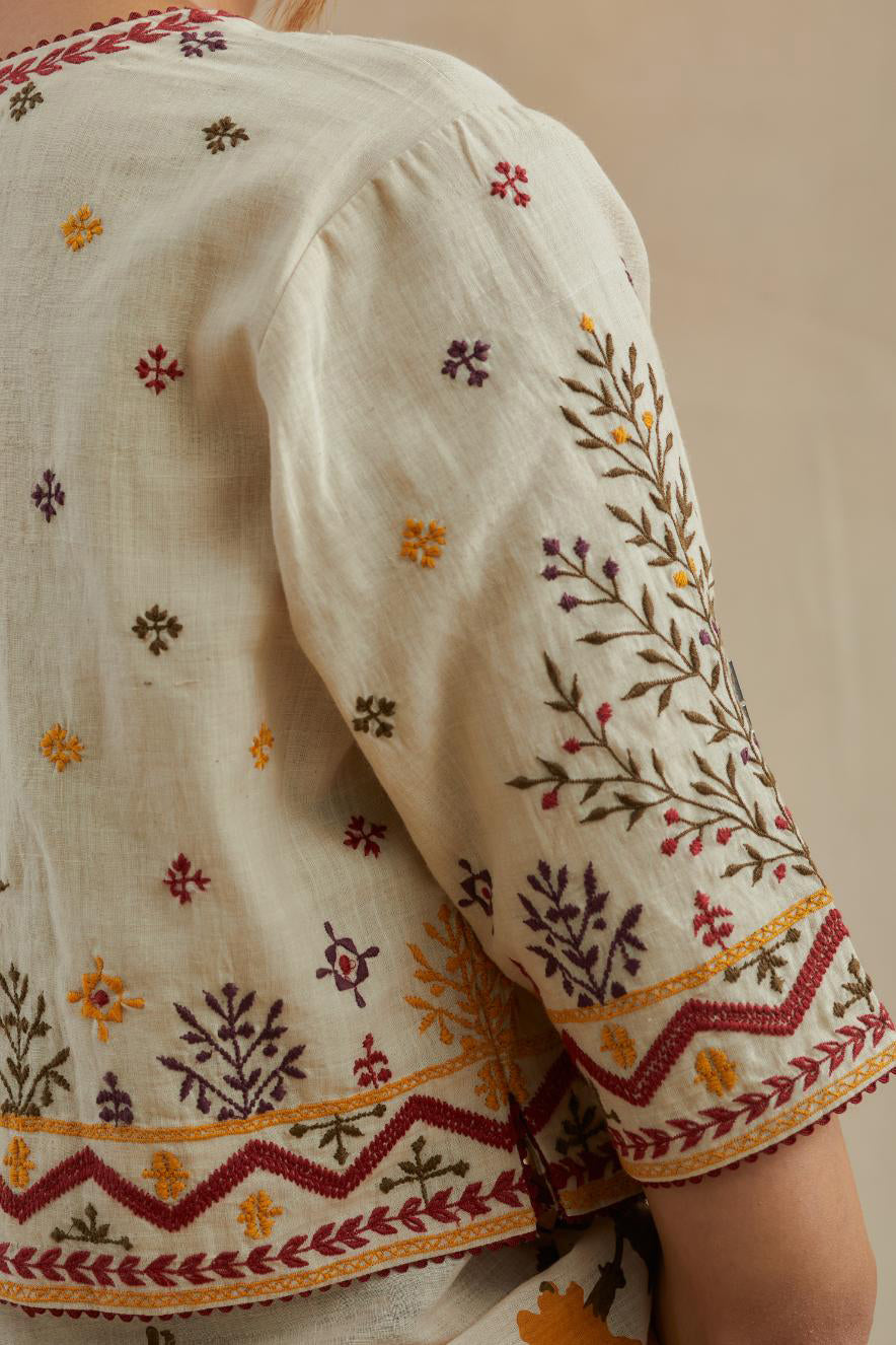 Beige cotton blouse with all-over multi colored thread embroidery.