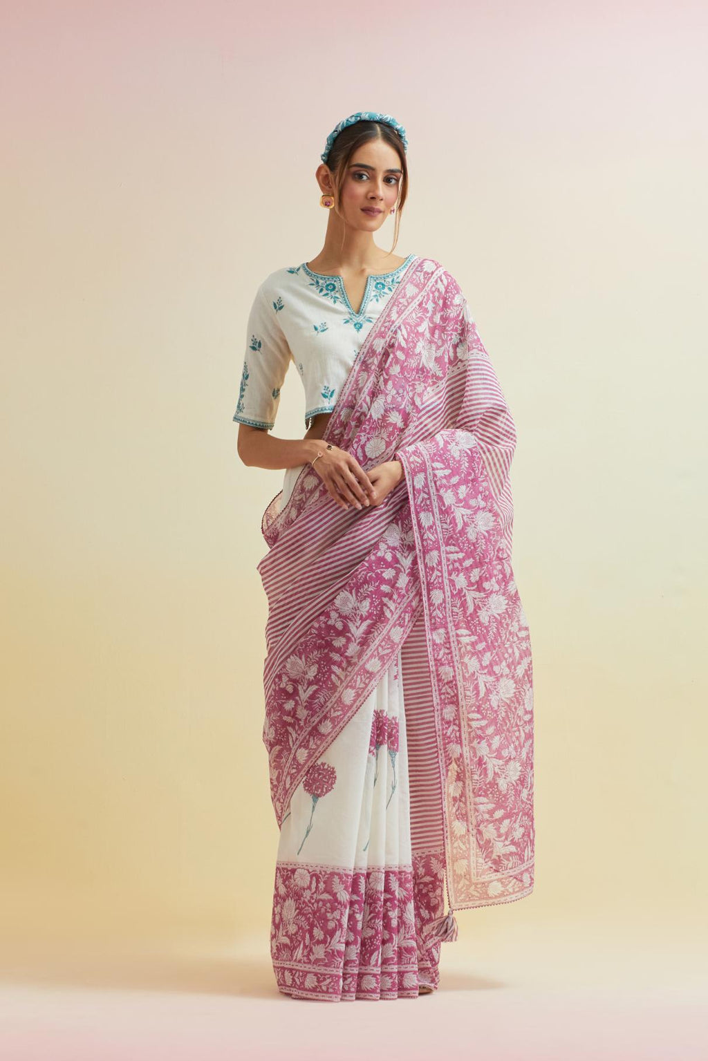 Orchid pink hand block cotton chanderi saree, highlighted with all-over carnation flower print, paired with off-white cotton blouse with all-over tropical teal thread embroidery.