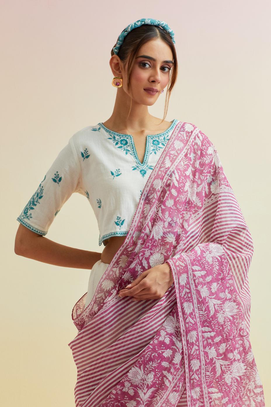 Orchid pink hand block cotton chanderi saree, highlighted with all-over carnation flower print, paired with off-white cotton blouse with all-over tropical teal thread embroidery.