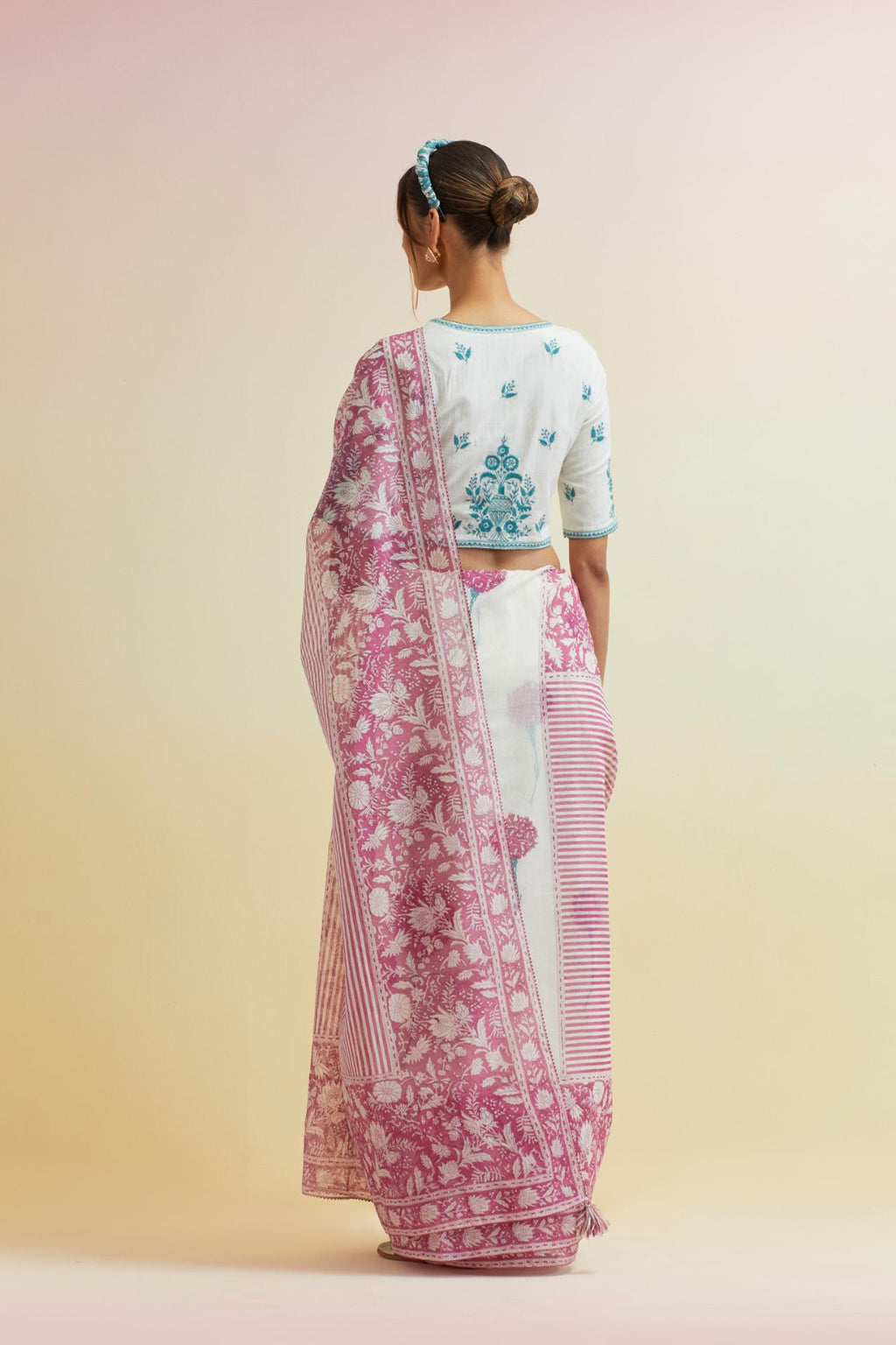 Orchid pink hand block cotton chanderi saree, highlighted with all-over carnation flower print, paired with off-white cotton blouse with all-over tropical teal thread embroidery.