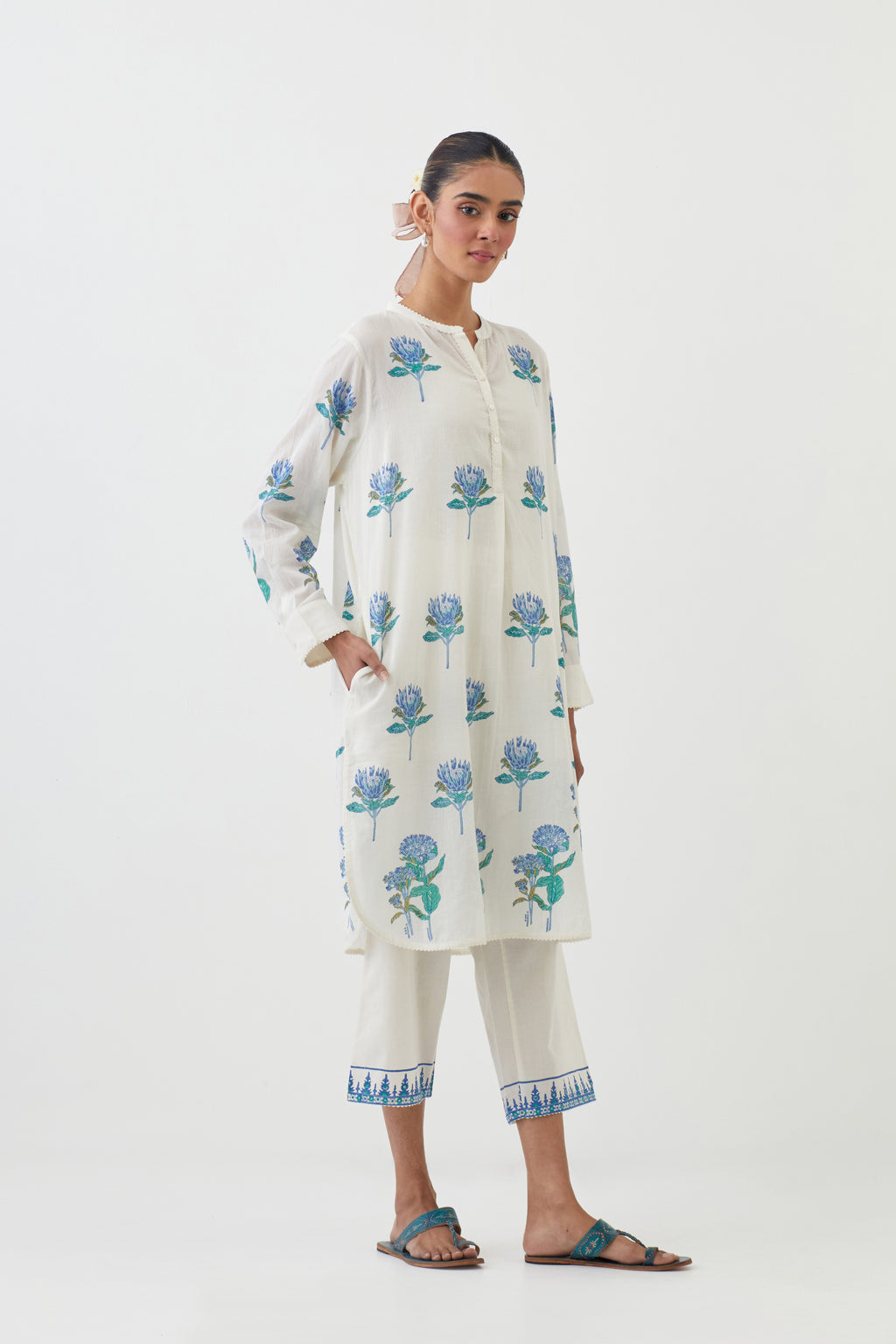 Off white cotton straight short kurta with all-over blue colored flower, paired with off white Cotton straight ankle length pants with hand block print border detail at hem.
