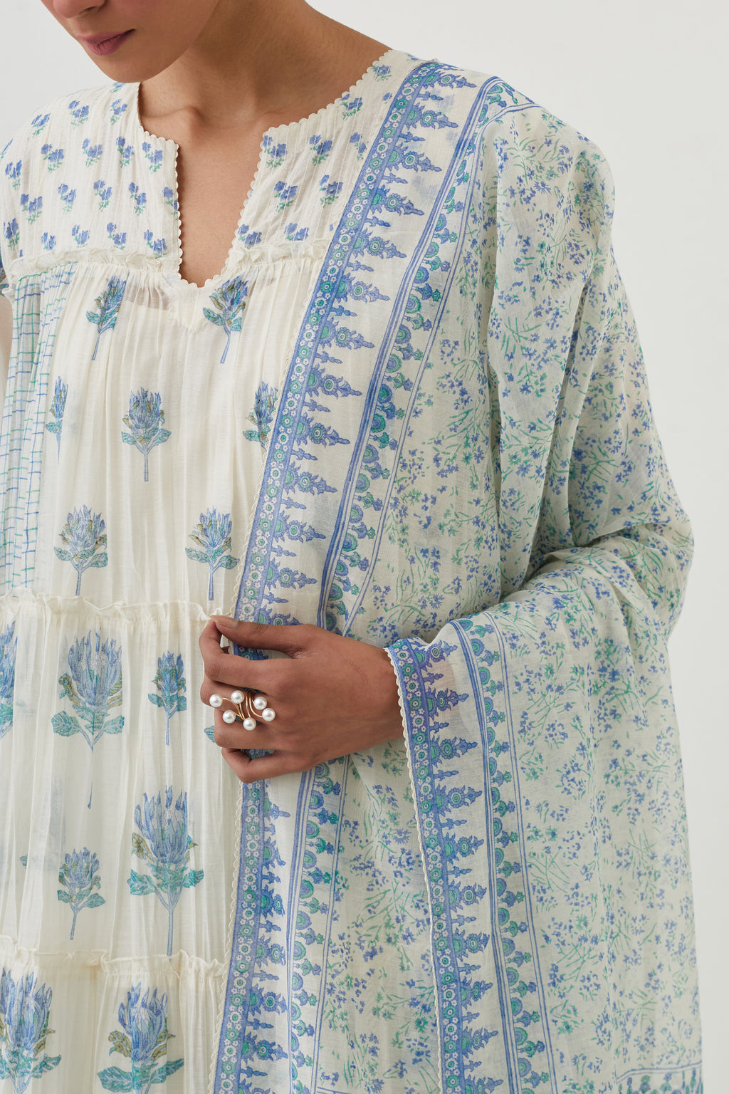 Off white hand block printed multi-tiered kurta set with quilted yoke and all-over blue colored flower.