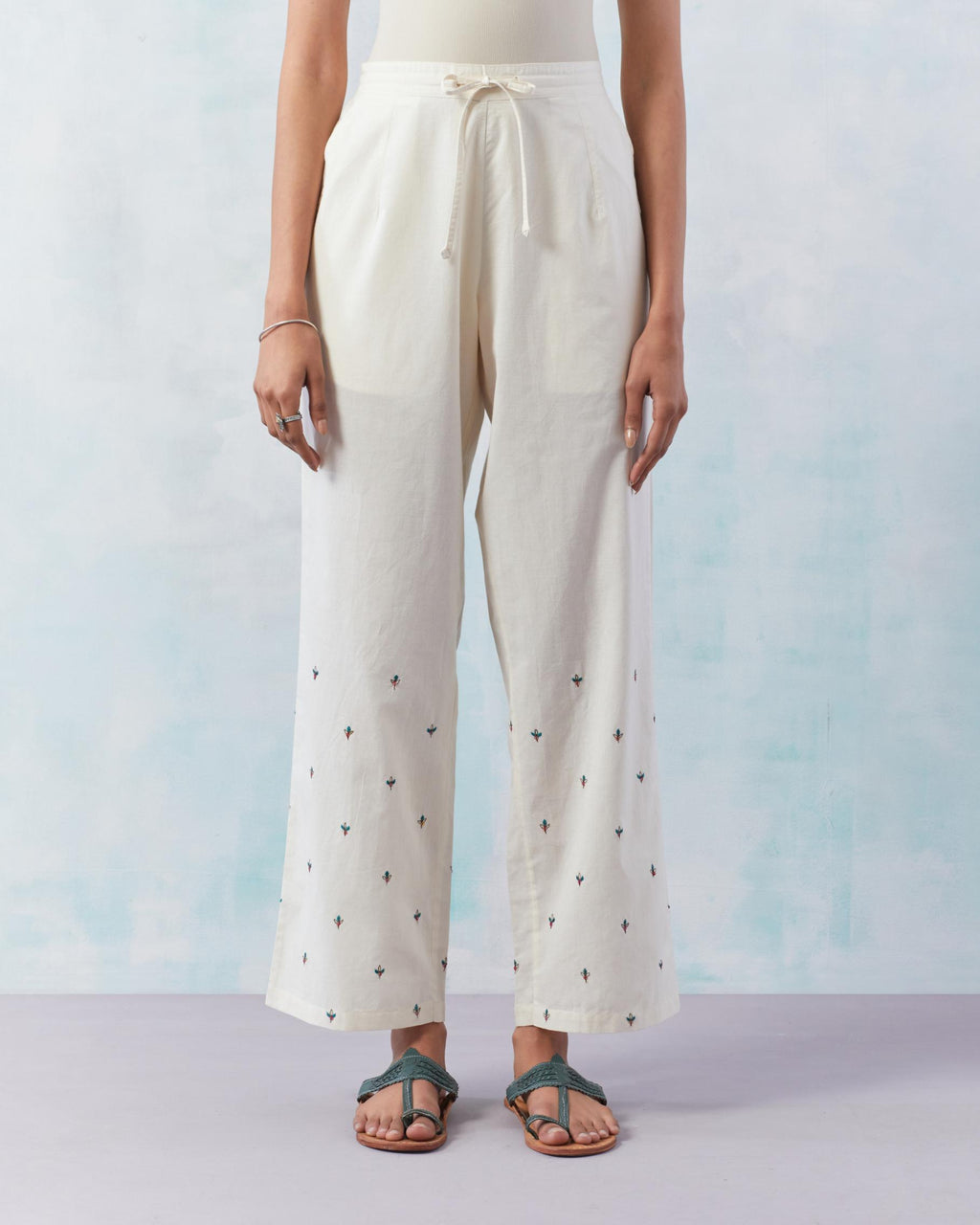 Off white cotton straight pants detailed with small flower embroidery at bottom.