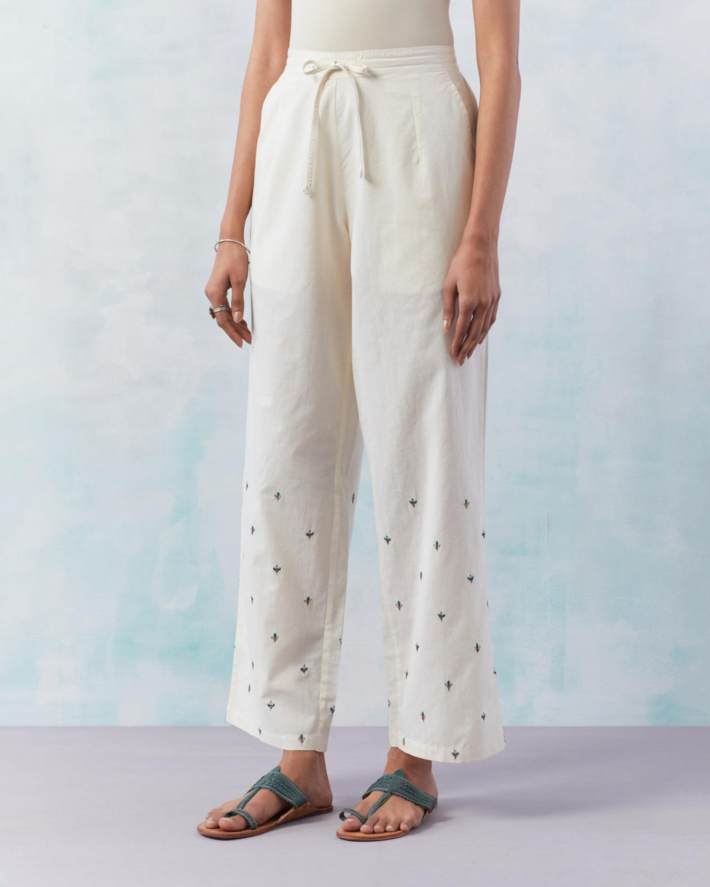 Off white cotton straight pants detailed with small flower embroidery at bottom.
