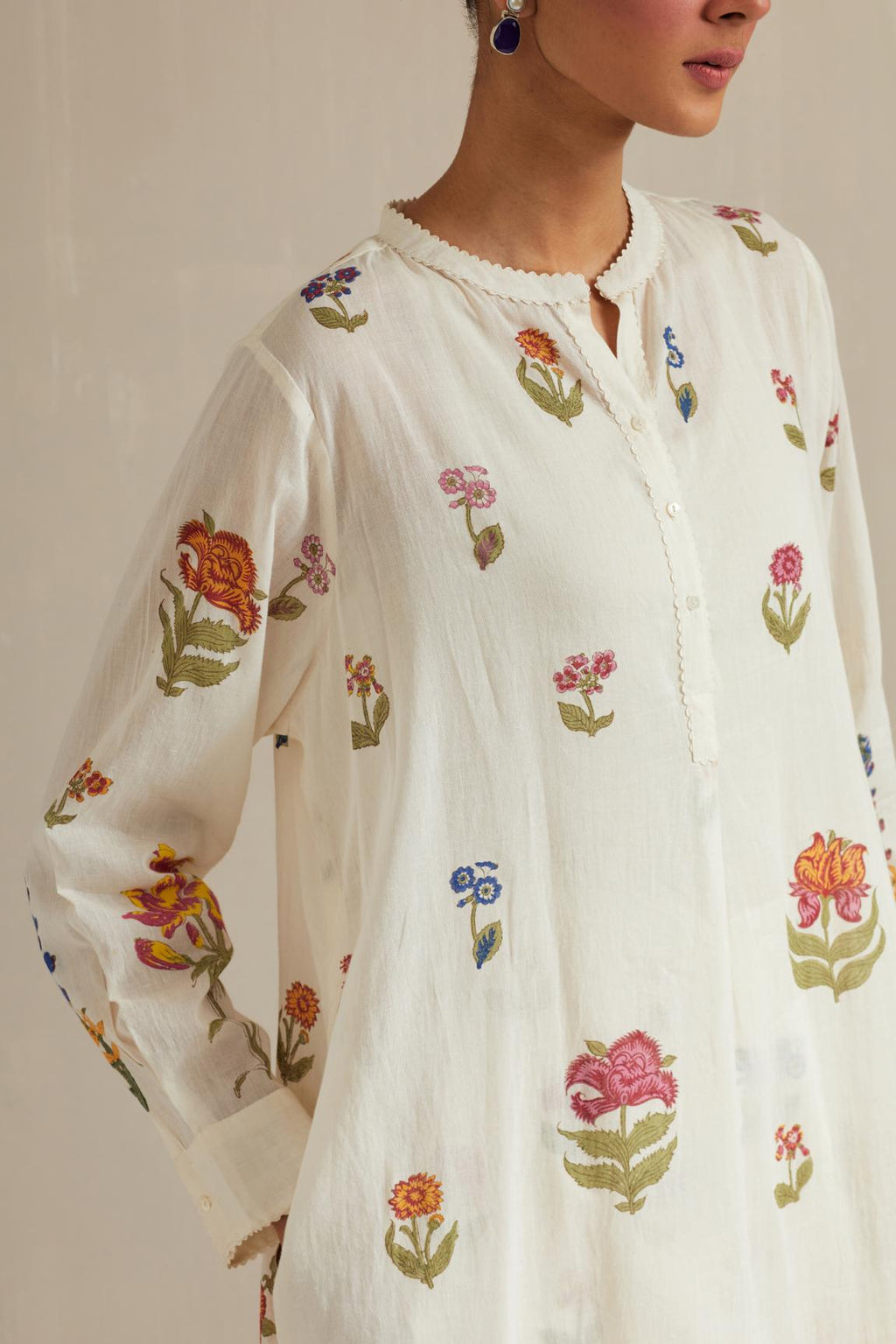Off white cotton straight short kurta with all-over multi colored flower, paired with off white hand block printed Cotton straight ankle length pants with all-over multi colored flower.