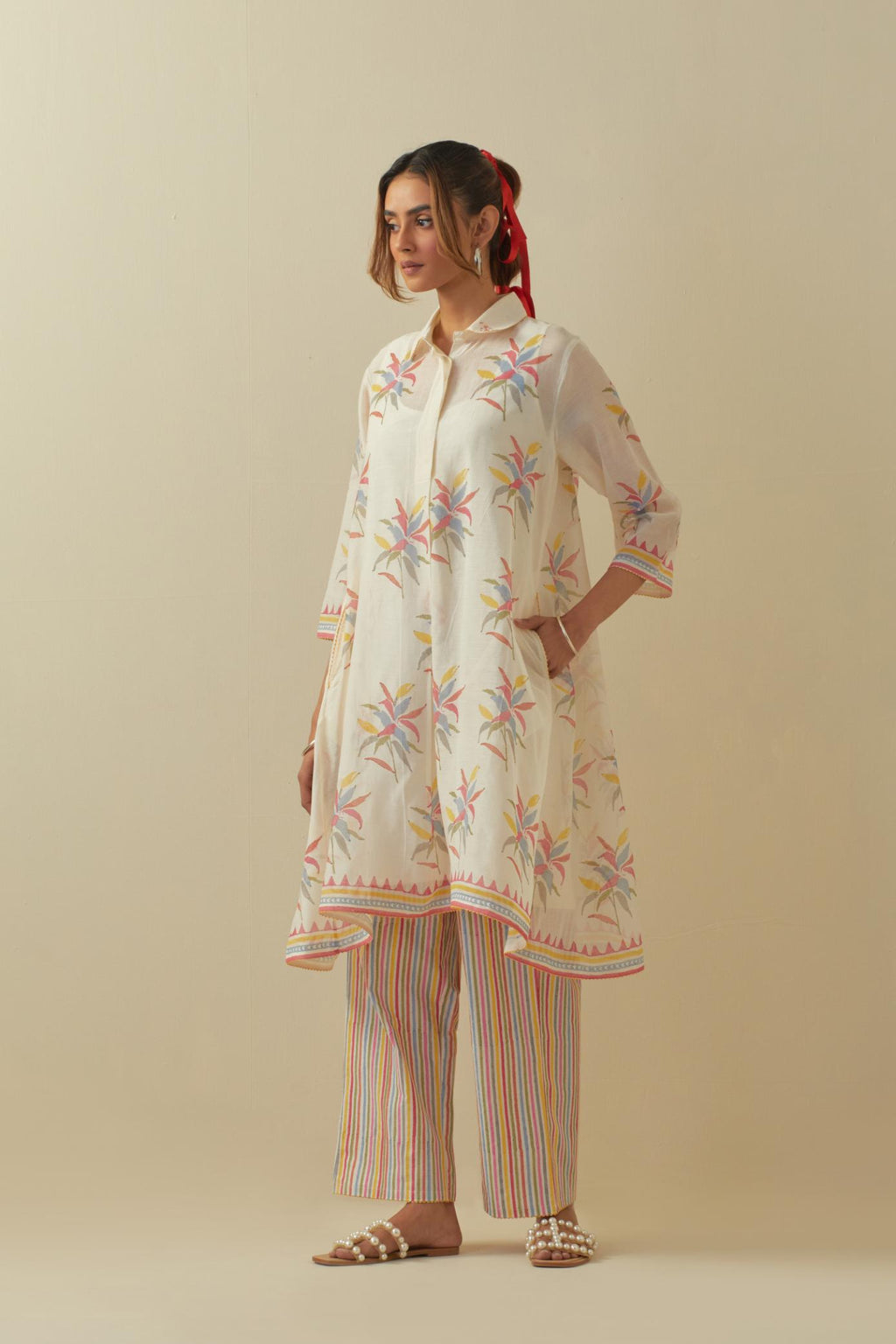 Off white hand block printed A-line short kurta with all-over multi colored flower boota, paired with multi colored striped hand block printed cotton straight pants.