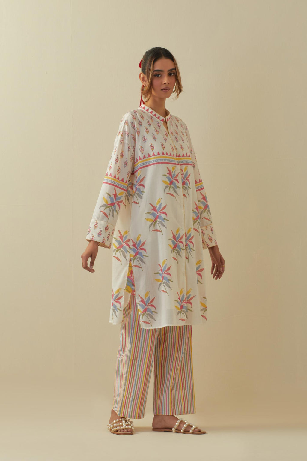 Off white cotton straight short kurta with all-over multi colored flower boota, paired with multi colored striped hand block printed cotton straight pants.