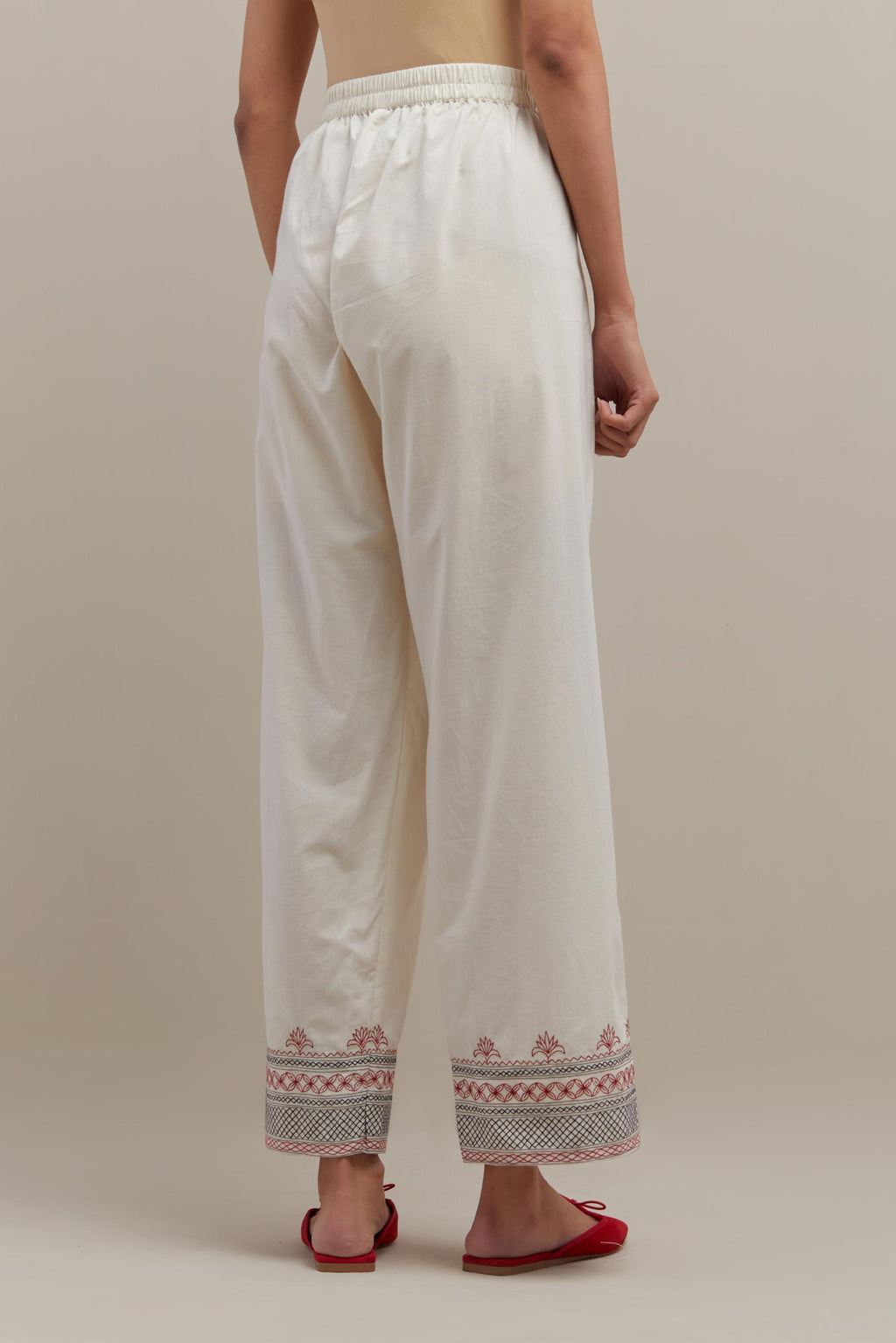 Off white straight pants with quilted embroidery at bottom hem.