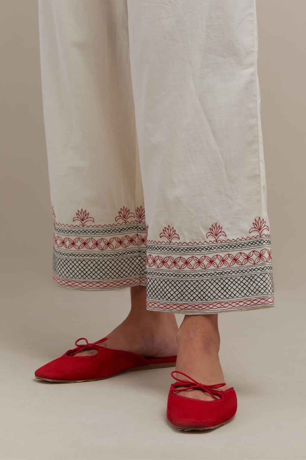 Off white straight pants with quilted embroidery at bottom hem.