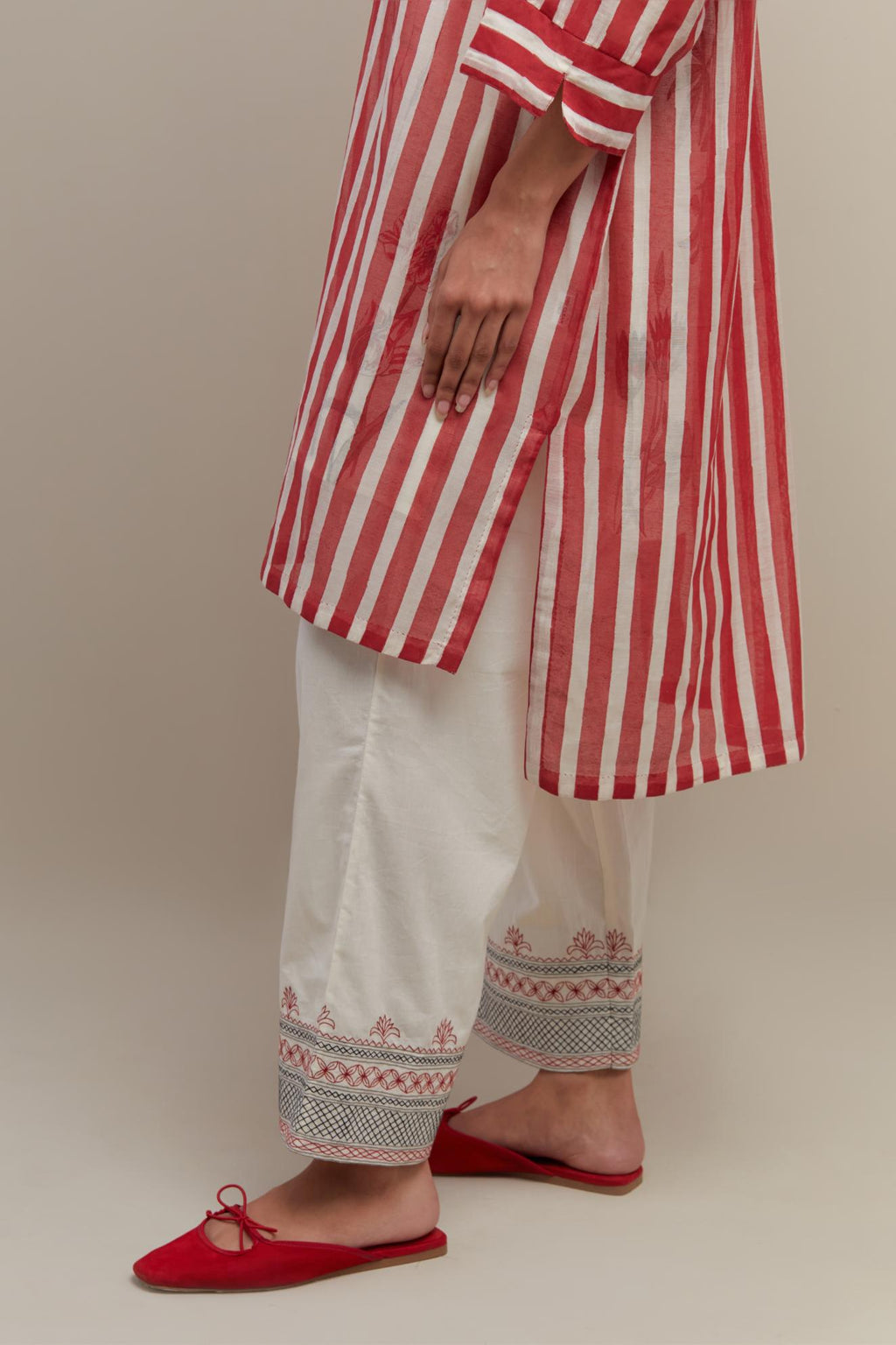 Red & off-white cotton chanderi hand block printed easy fit kurta with band collar neckline, paired with off white straight pants with quilted embroidery at bottom hem.