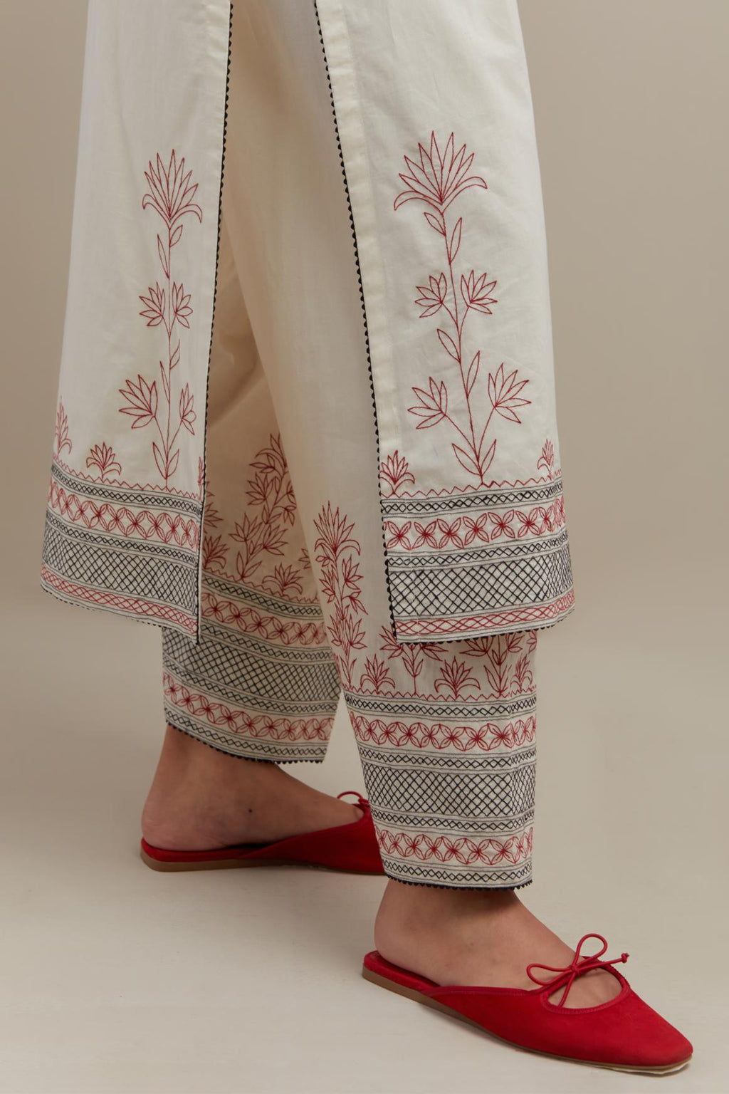 Off white cotton straight kurta set with red & black embroidery at neck, hem and sleeves.