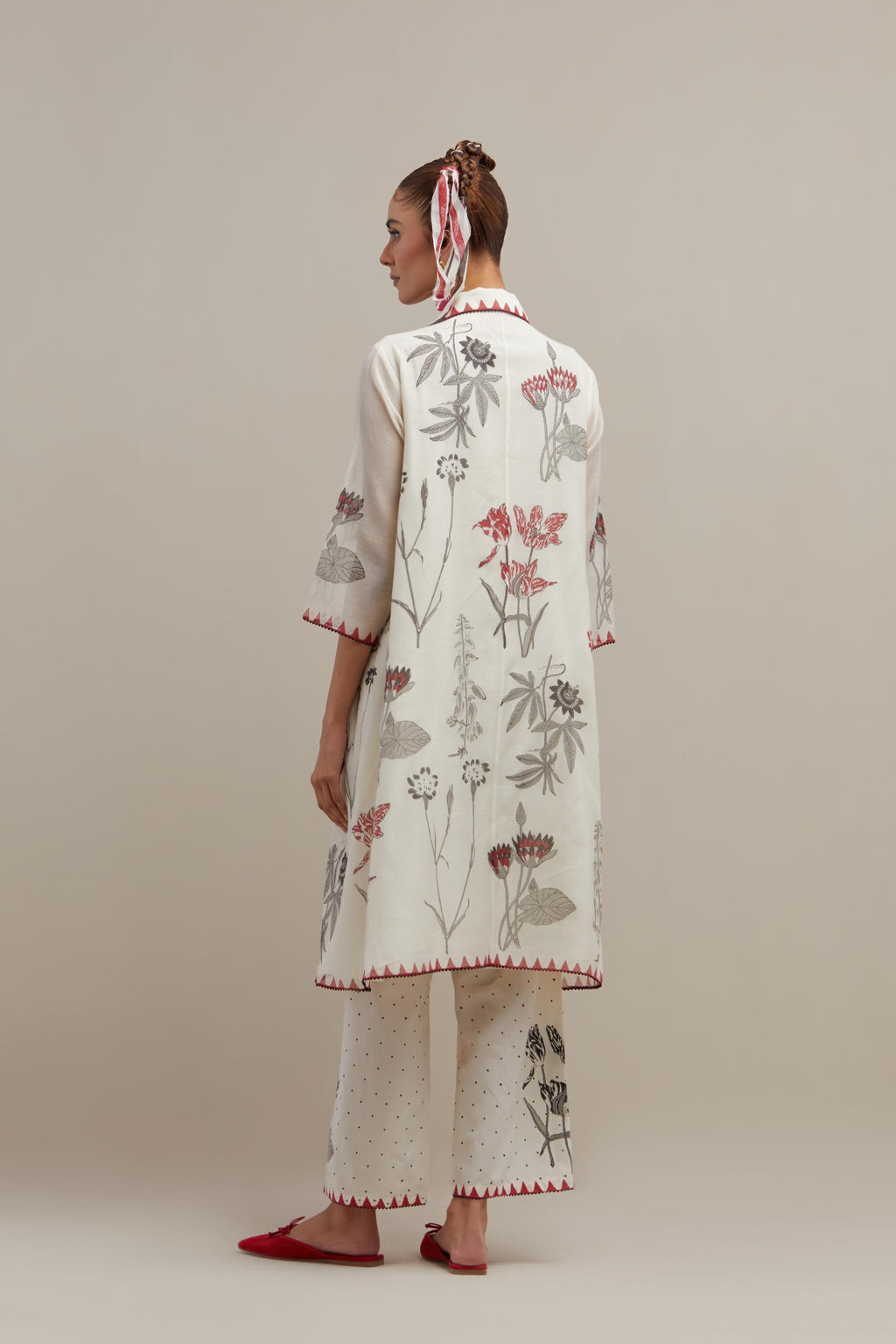 Off white cotton chanderi hand block printed A-line short kurta with red & black colored flower boota, paired with off white cotton straight pants with all-over black & red hand block print.