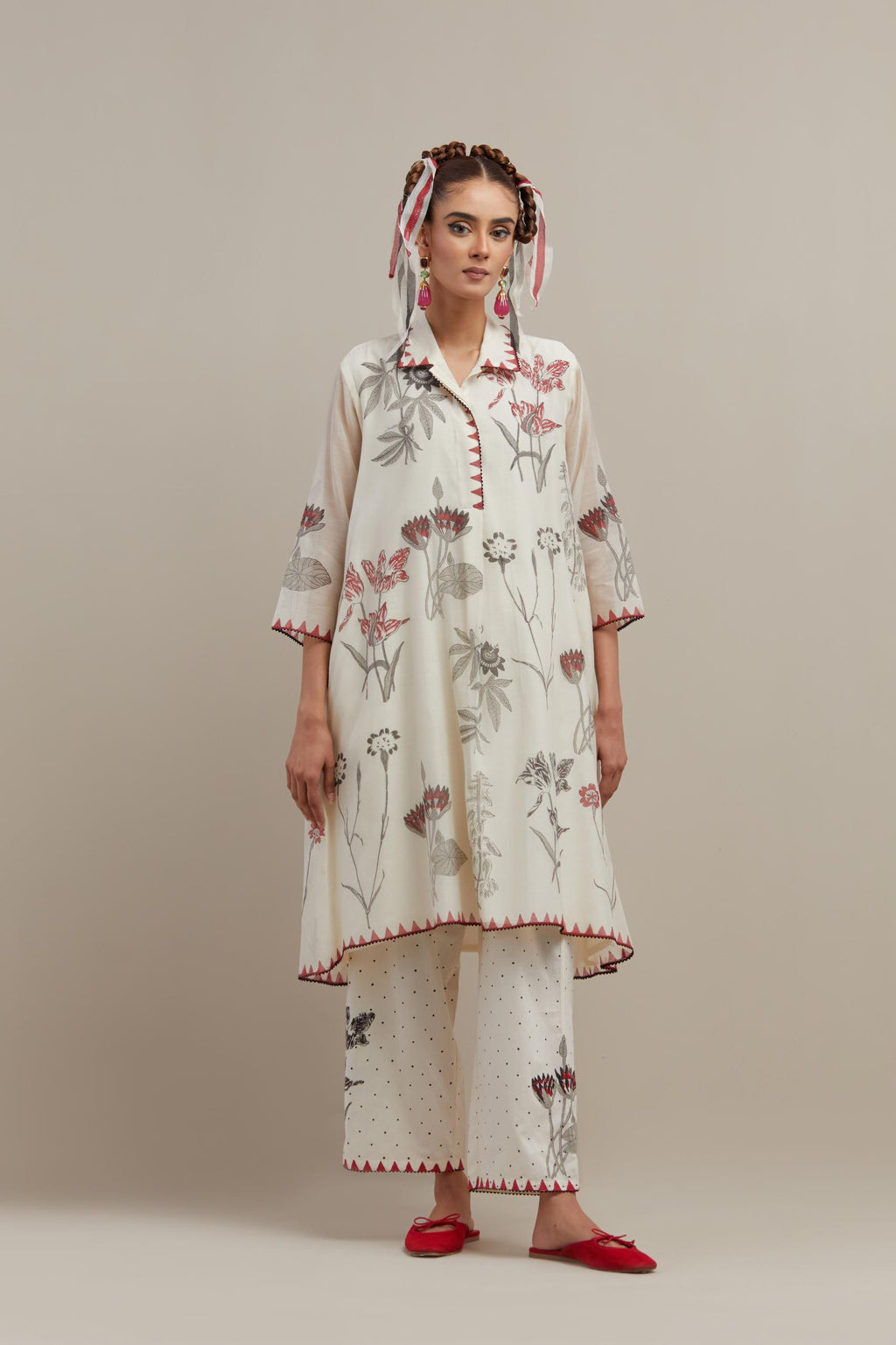 Off white cotton chanderi hand block printed A-line short kurta with red & black colored flower boota, paired with off white cotton straight pants with all-over black & red hand block print.