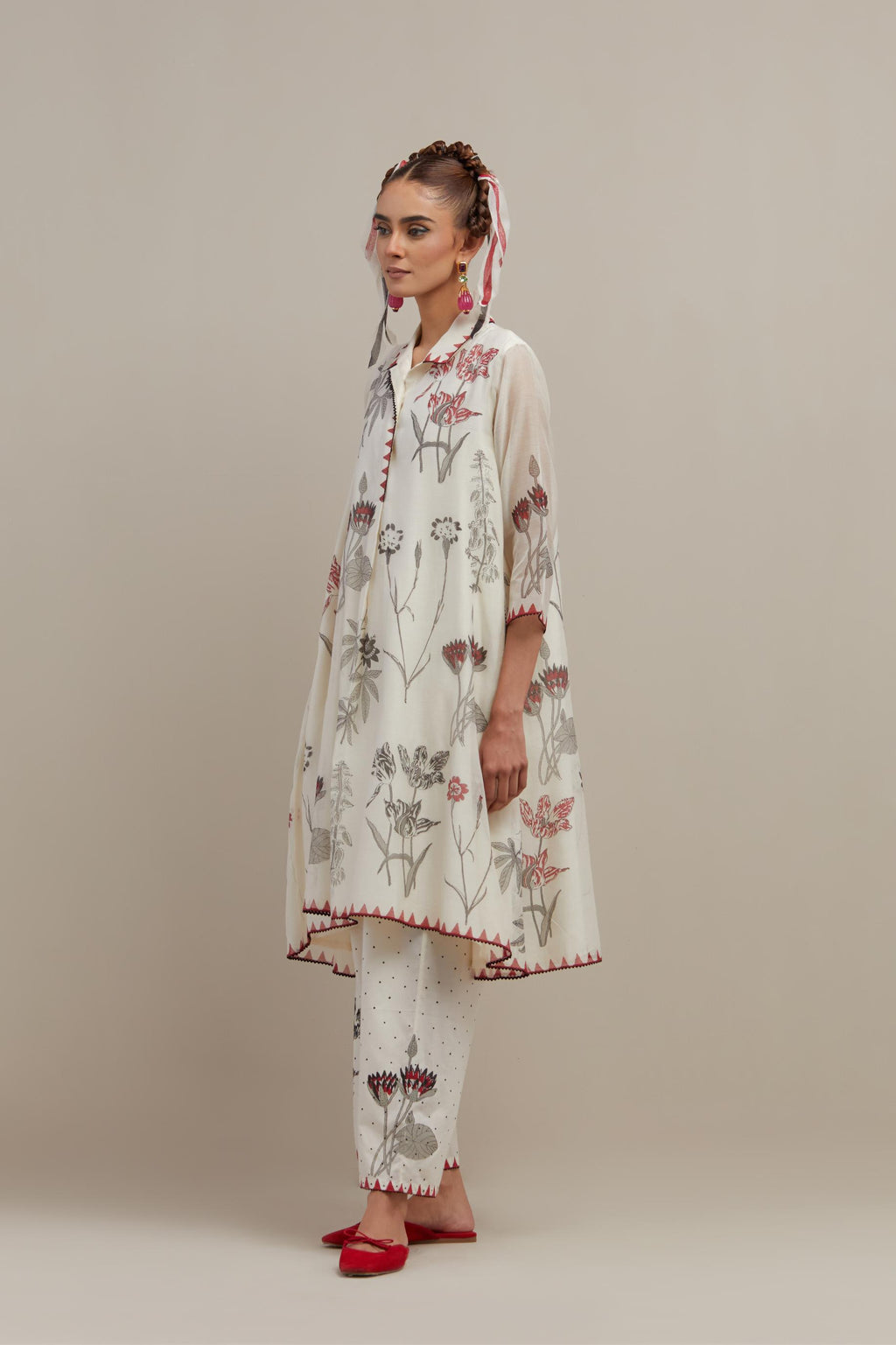 Off white cotton chanderi hand block printed A-line short kurta with red & black colored flower boota, paired with off white cotton straight pants with all-over black & red hand block print.