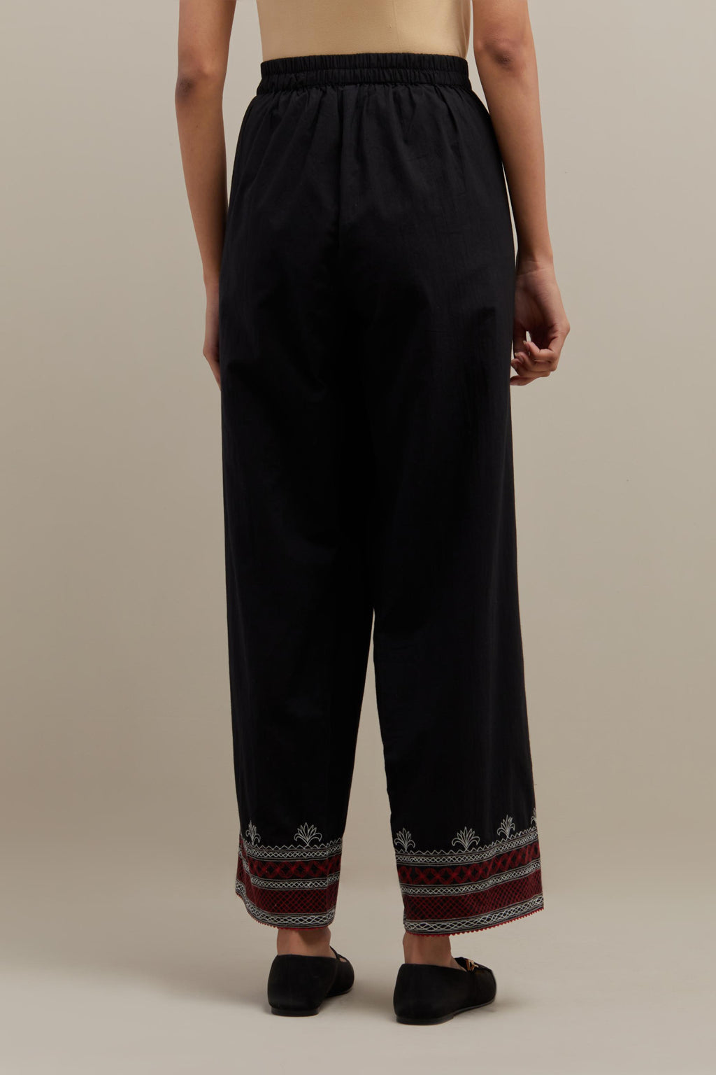 Black straight pants with quilted embroidery at bottom hem.