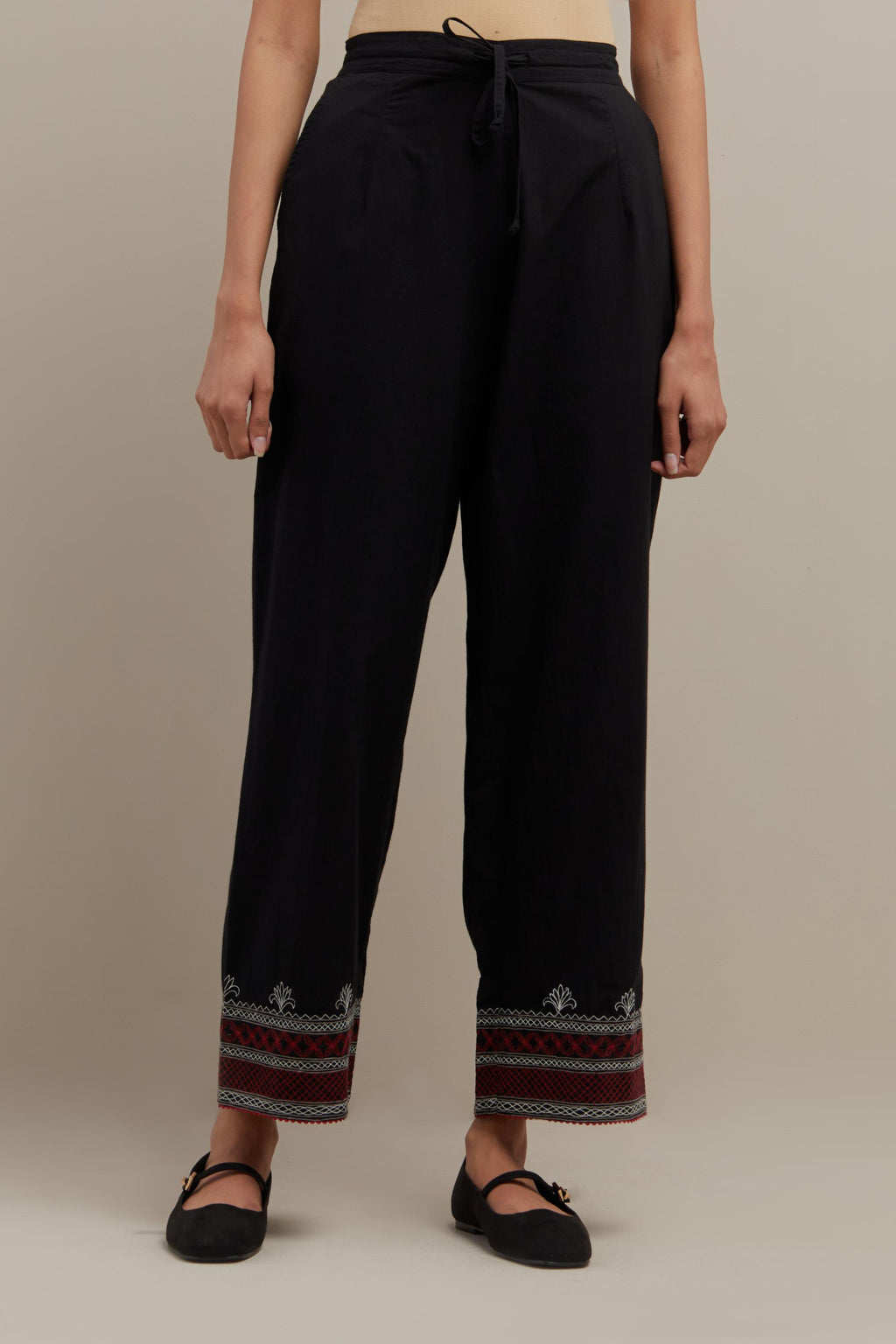 Black straight pants with quilted embroidery at bottom hem.