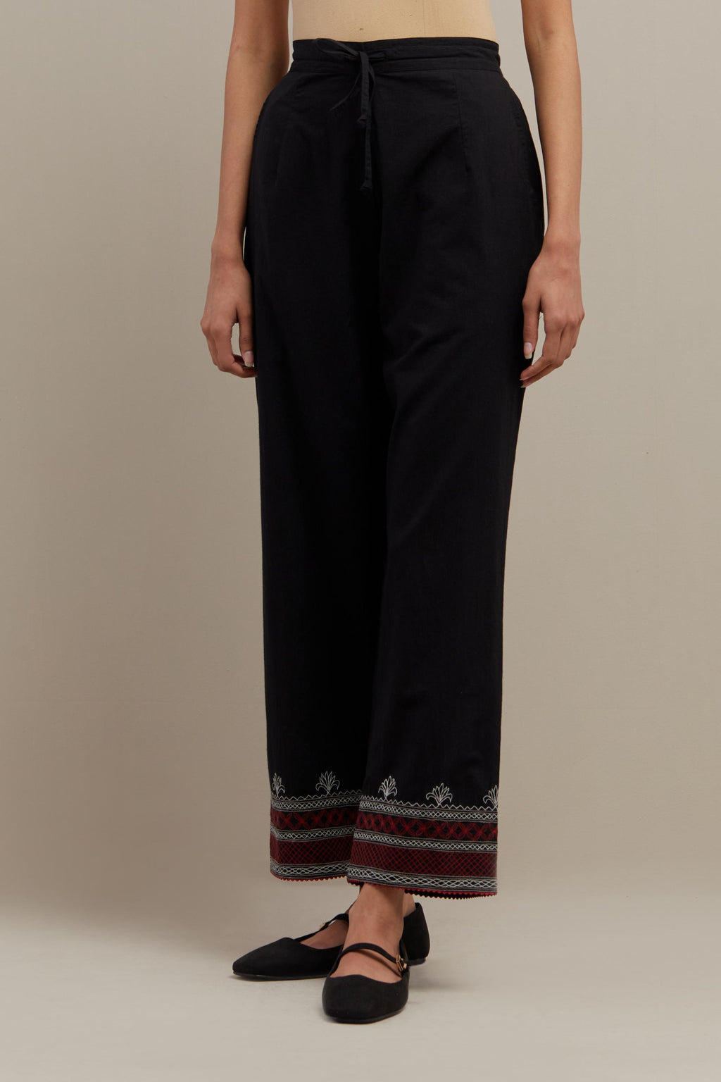 Black straight pants with quilted embroidery at bottom hem.