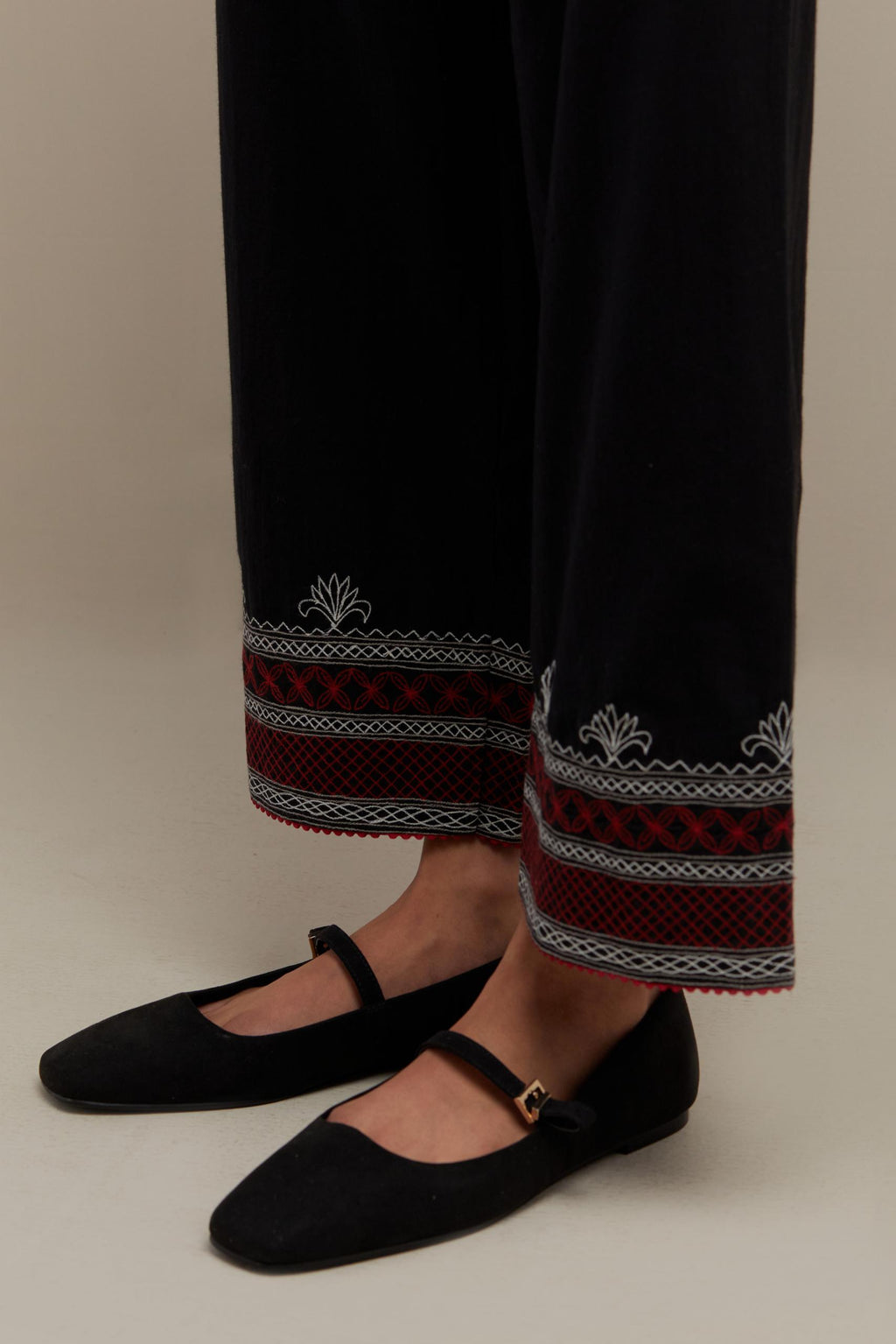 Black straight pants with quilted embroidery at bottom hem.