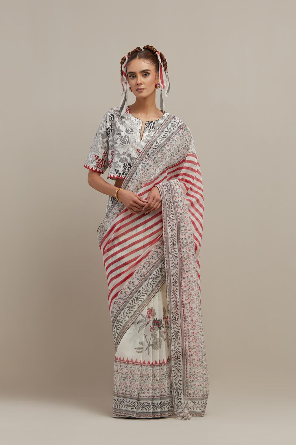 Off white cotton chanderi saree, highlighted with all-over bold stripe and floral hand block print, paired with off-white hand block printed cotton blouse, paired with off-white cotton blouse with all-over red & black hand block print.