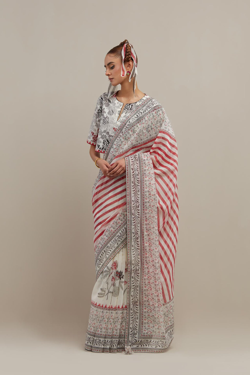 Off white cotton chanderi saree, highlighted with all-over bold stripe and floral hand block print, paired with off-white hand block printed cotton blouse, paired with off-white cotton blouse with all-over red & black hand block print.