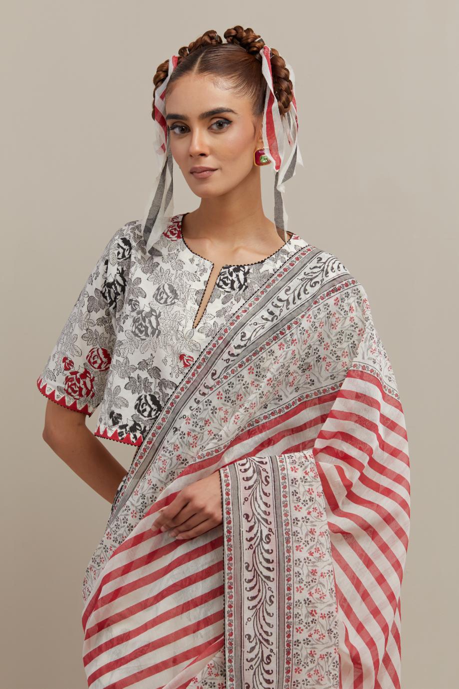 Off white cotton chanderi saree, highlighted with all-over bold stripe and floral hand block print, paired with off-white hand block printed cotton blouse, paired with off-white cotton blouse with all-over red & black hand block print.