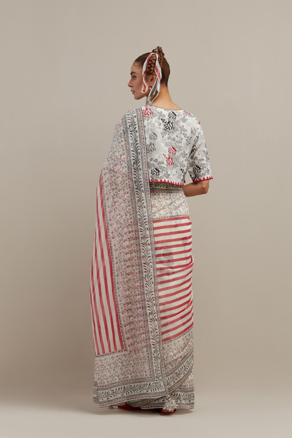 Off white cotton chanderi saree, highlighted with all-over bold stripe and floral hand block print, paired with off-white hand block printed cotton blouse, paired with off-white cotton blouse with all-over red & black hand block print.