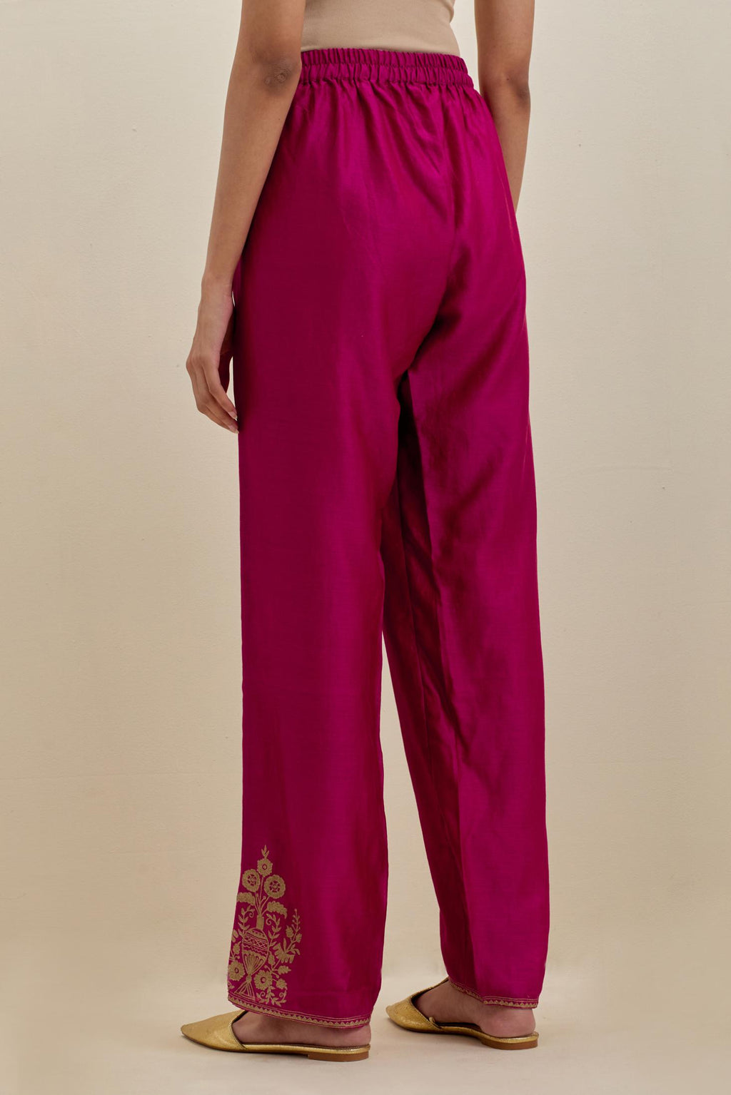 Dark fuchsia silk chanderi straight pants with dull gold zari embroidered boota at sides and narrow border detailing at bottom hem.