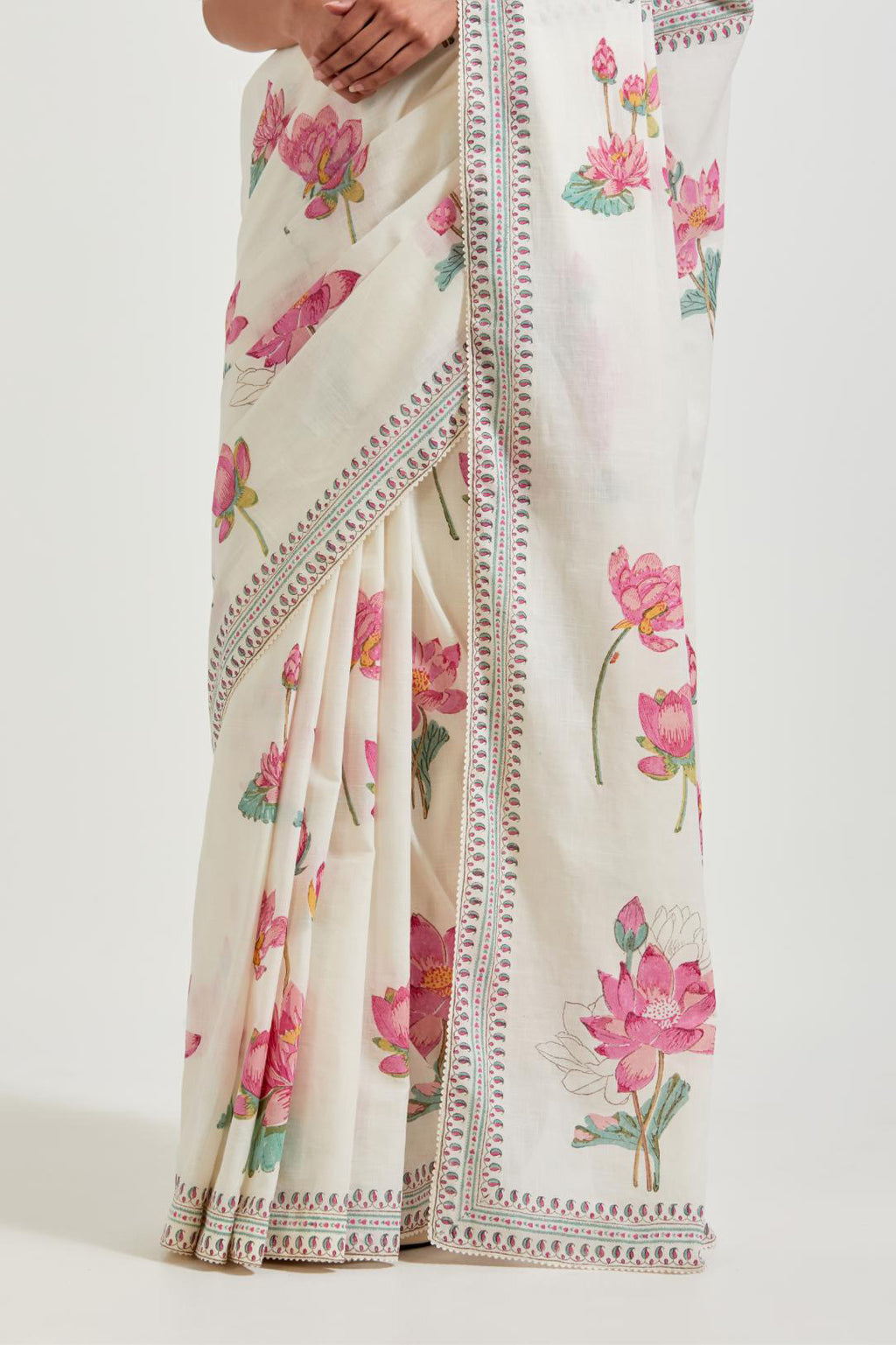 Off white cotton saree, highlighted with all-over pink & green lotus flower hand block print, paired with off-white cotton blouse with all-over pink & green small lotus flower hand block print.