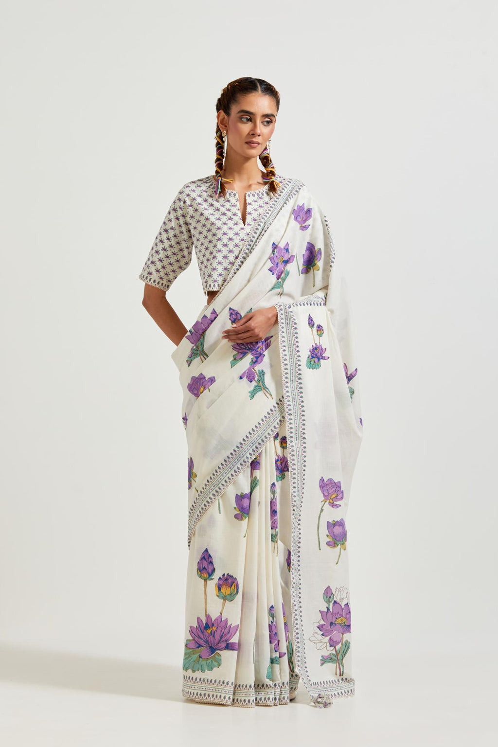 Off white cotton saree, highlighted with all-over purple & green lotus flower hand block print, paired with off-white cotton blouse with all-over purple & green small lotus flower hand block print.