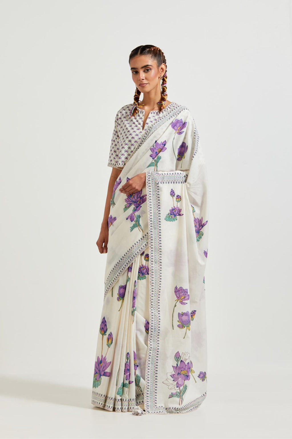 Off white cotton saree, highlighted with all-over purple & green lotus flower hand block print, paired with off-white cotton blouse with all-over purple & green small lotus flower hand block print.