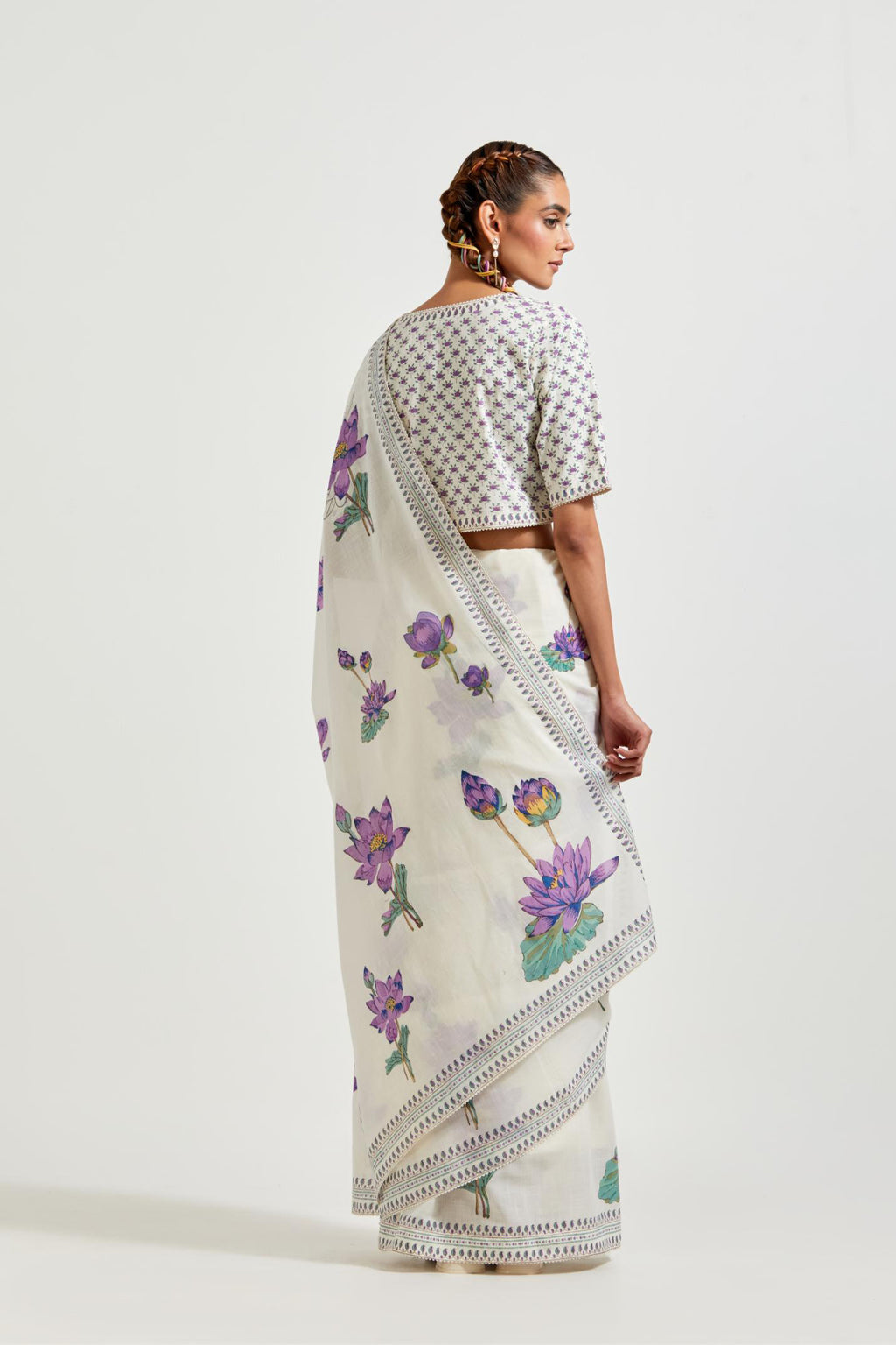 Off white cotton saree, highlighted with all-over purple & green lotus flower hand block print, paired with off-white cotton blouse with all-over purple & green small lotus flower hand block print.